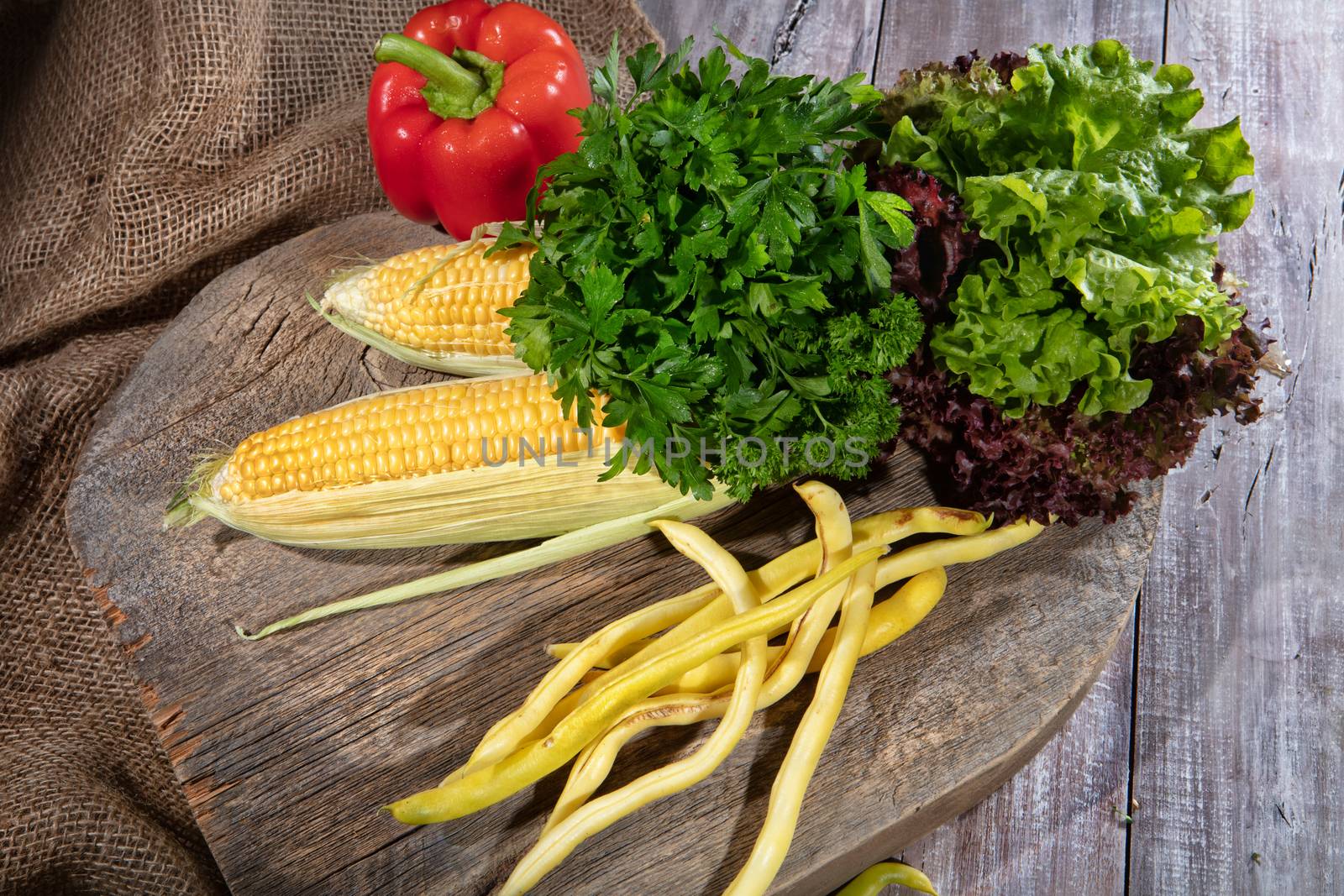 Maize, greenery, pea and tomato on a wooden table