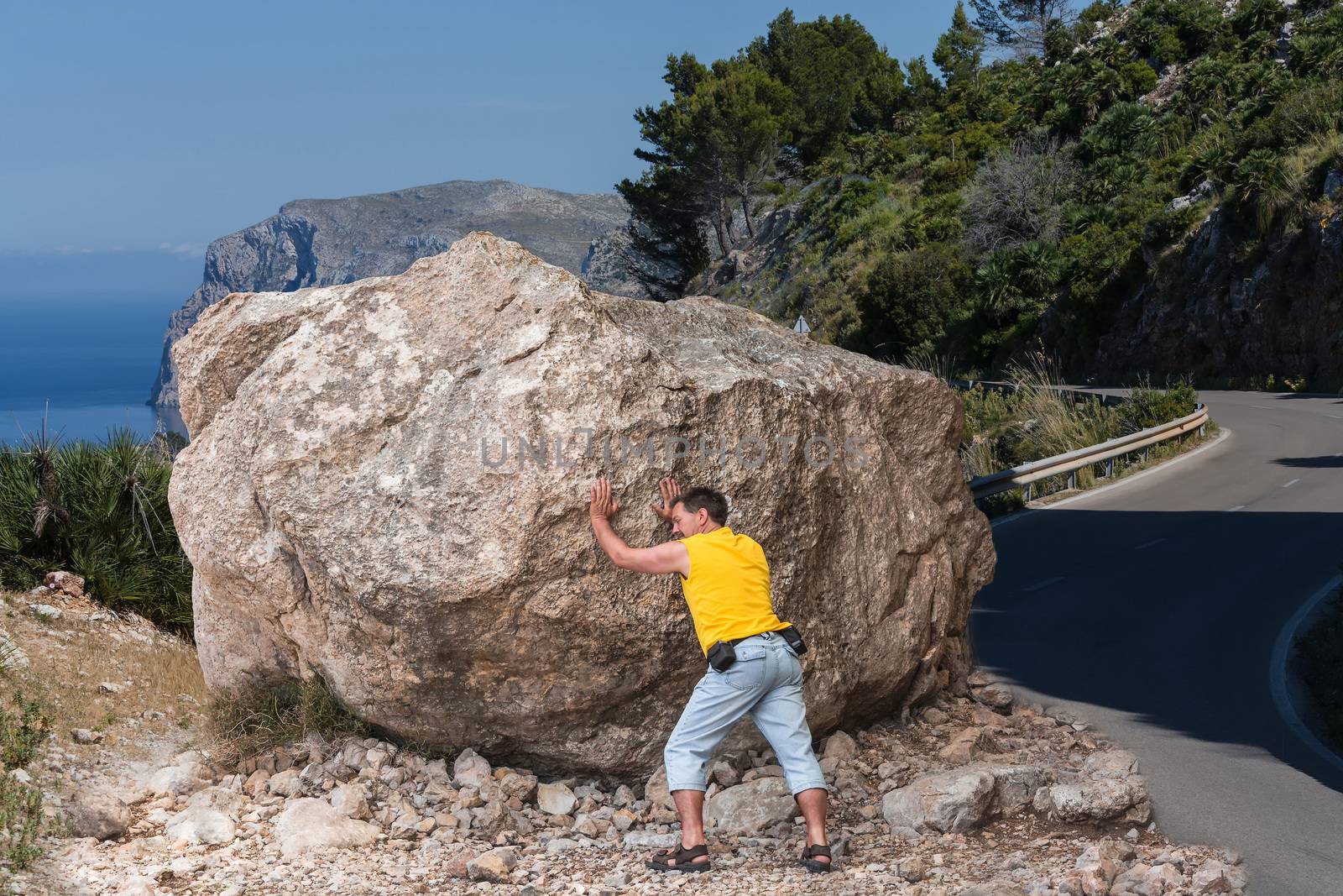 Man tries to push away a large boulder.        by JFsPic