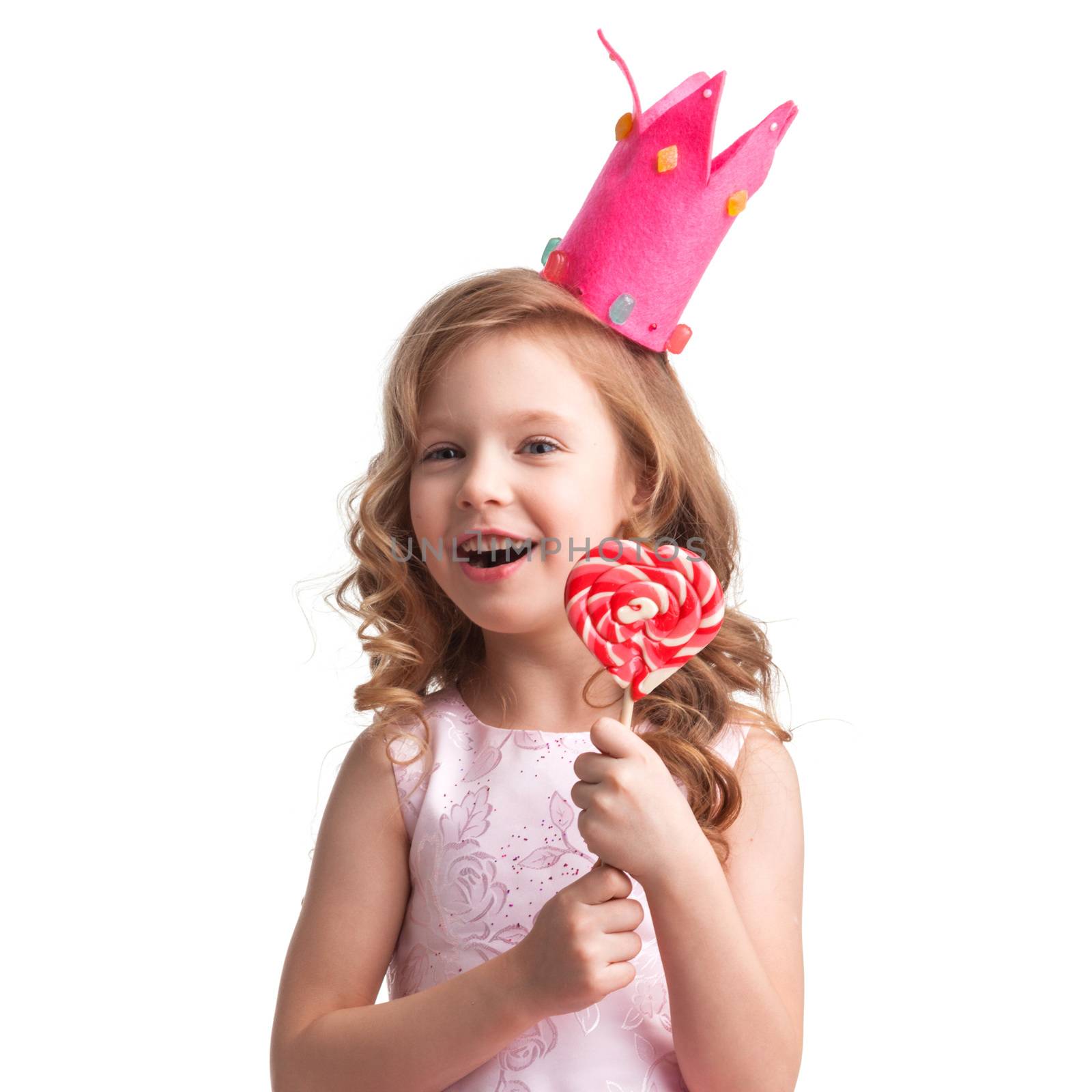 Beautiful little candy princess girl in crown holding big pink heart shaped lollipop and smiling