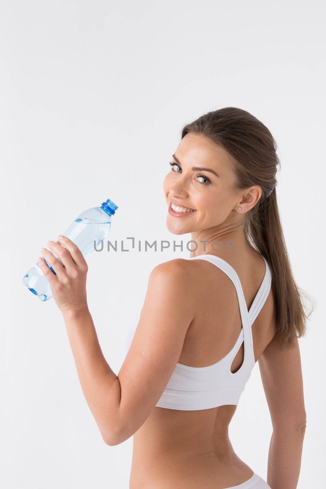 Beautiful woman in white sport lingerie with bottle of water over white