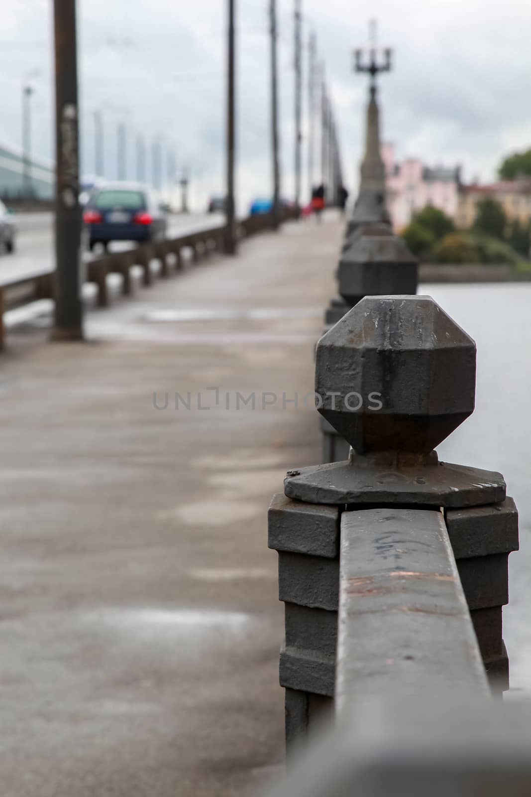 Fragment of Akmens bridge in Riga, Latvia. Stone bridge railings, blurred car traffic in the background. Stone bridge in Riga city.
