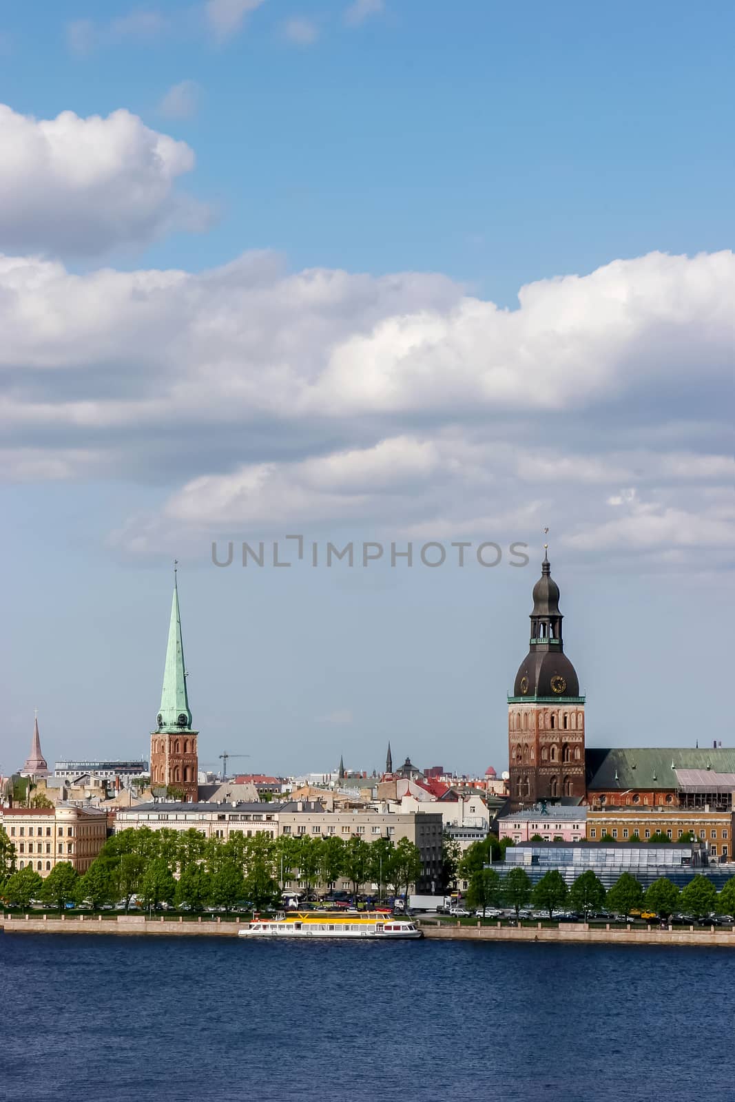 Riga, capital city of Latvia. View of St Peter's Church and St. Jacob's Cathedral. View of Old Riga with Daugava river in the foreground. City Riga with background of blue sky. View of Riga with ld buildings and historic architecture.
