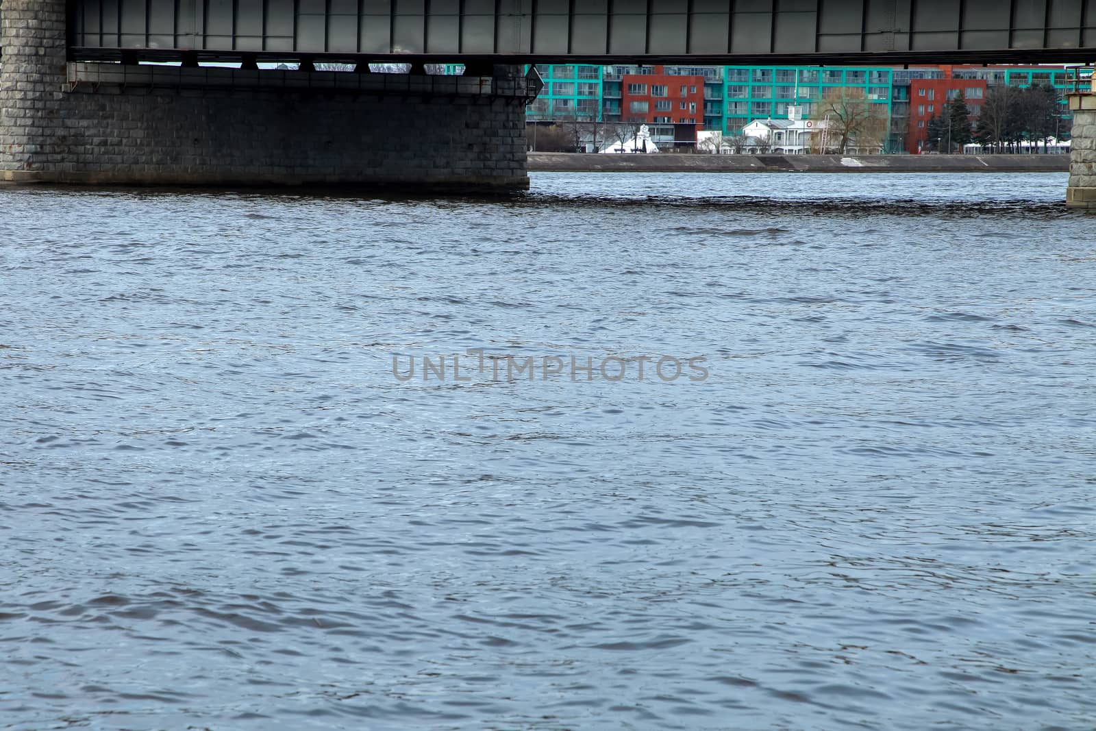 View of the Akmens bridge from the 11th November Embankment. Behind the Akmens bridge- residential buildings. On the front is the river Daugava. River under bridge in center of Riga.