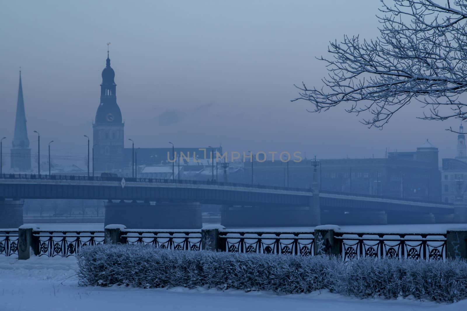 Riga view in winter; Riga, capital city of Latvia in winter time. View of  St. Jacob's Cathedral and Riga Dome Cathedral. View of Old Riga with frozen river Daugava in the foreground. City Riga with background of blue sky. 