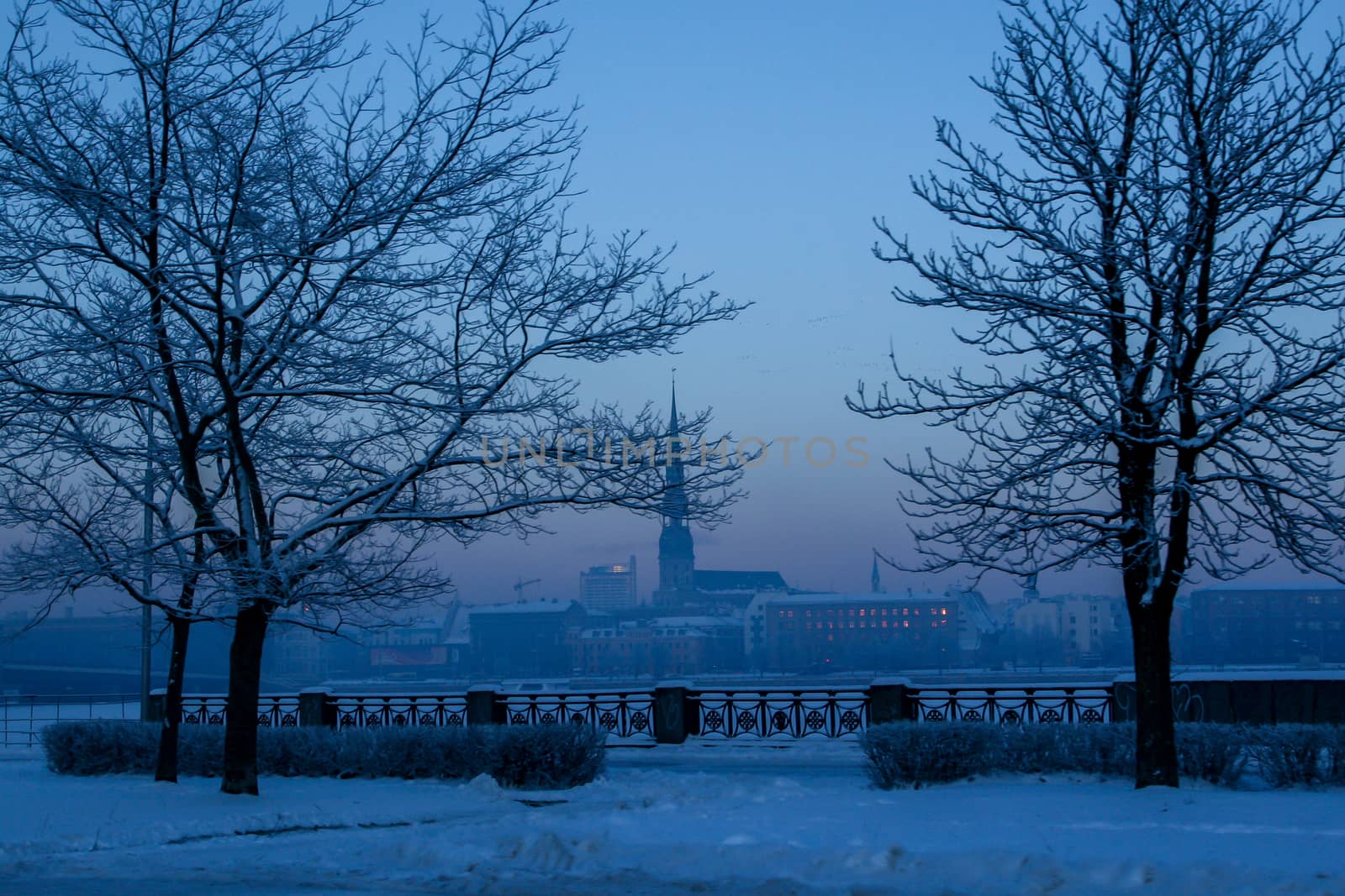 Riga view in winter; Riga, capital city of Latvia in winter time. View of St Peter's Church in winter. View of Old Riga with frozen river Daugava in the foreground. City Riga with background of blue sky. 