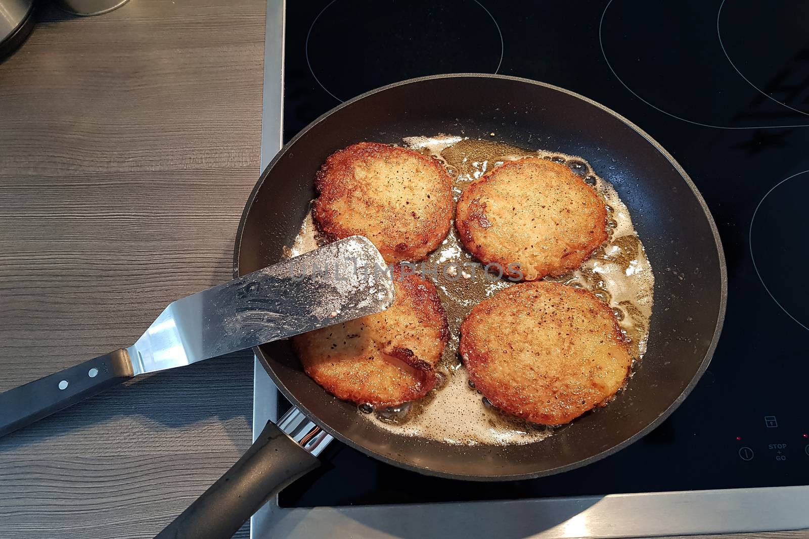 Potato pancakes in black frying pan, top view