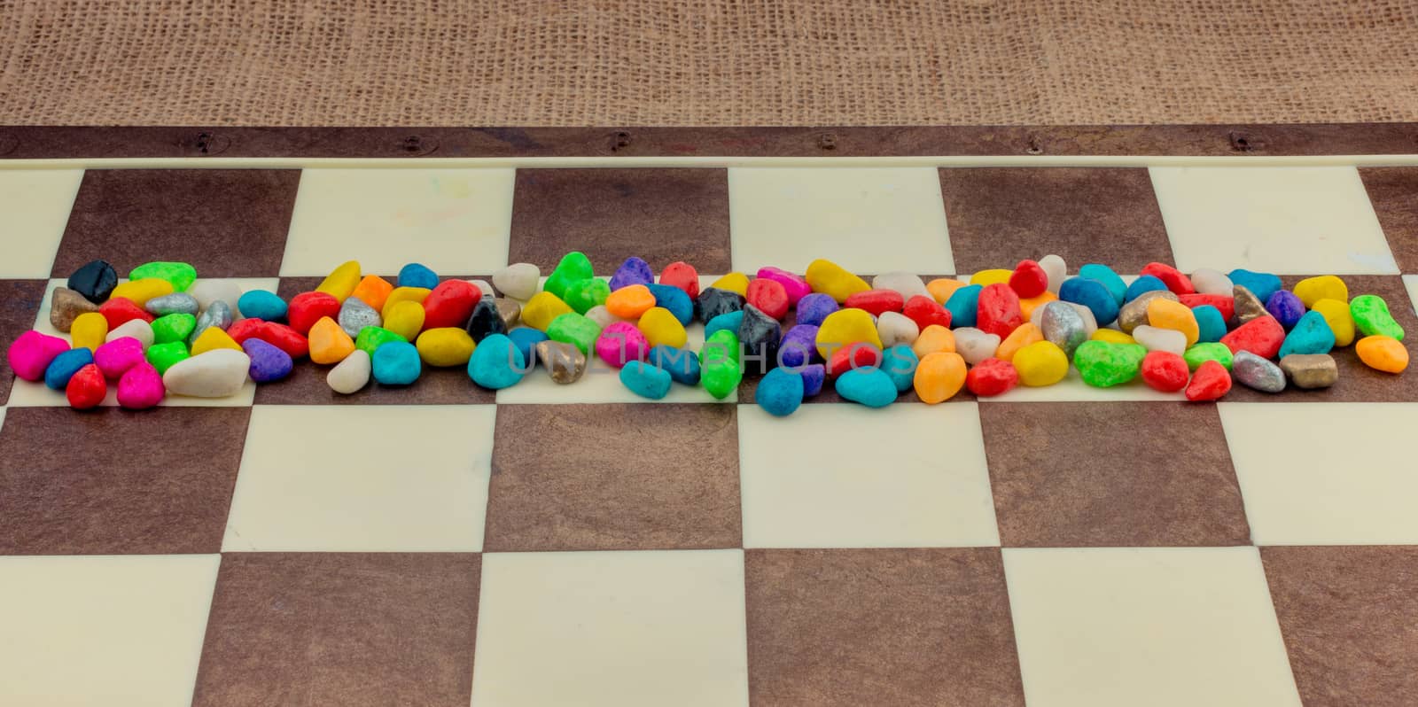 Colorful pebbles spread on checked board  by berkay