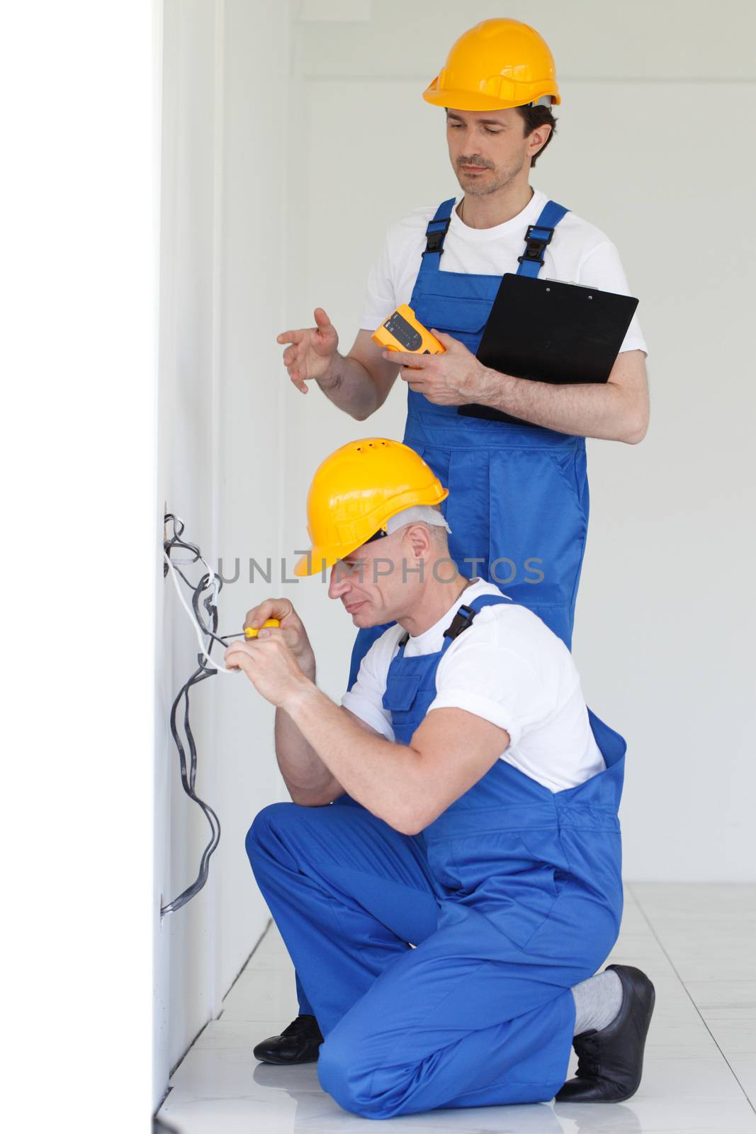 Two builders working with electricity indoors in new house