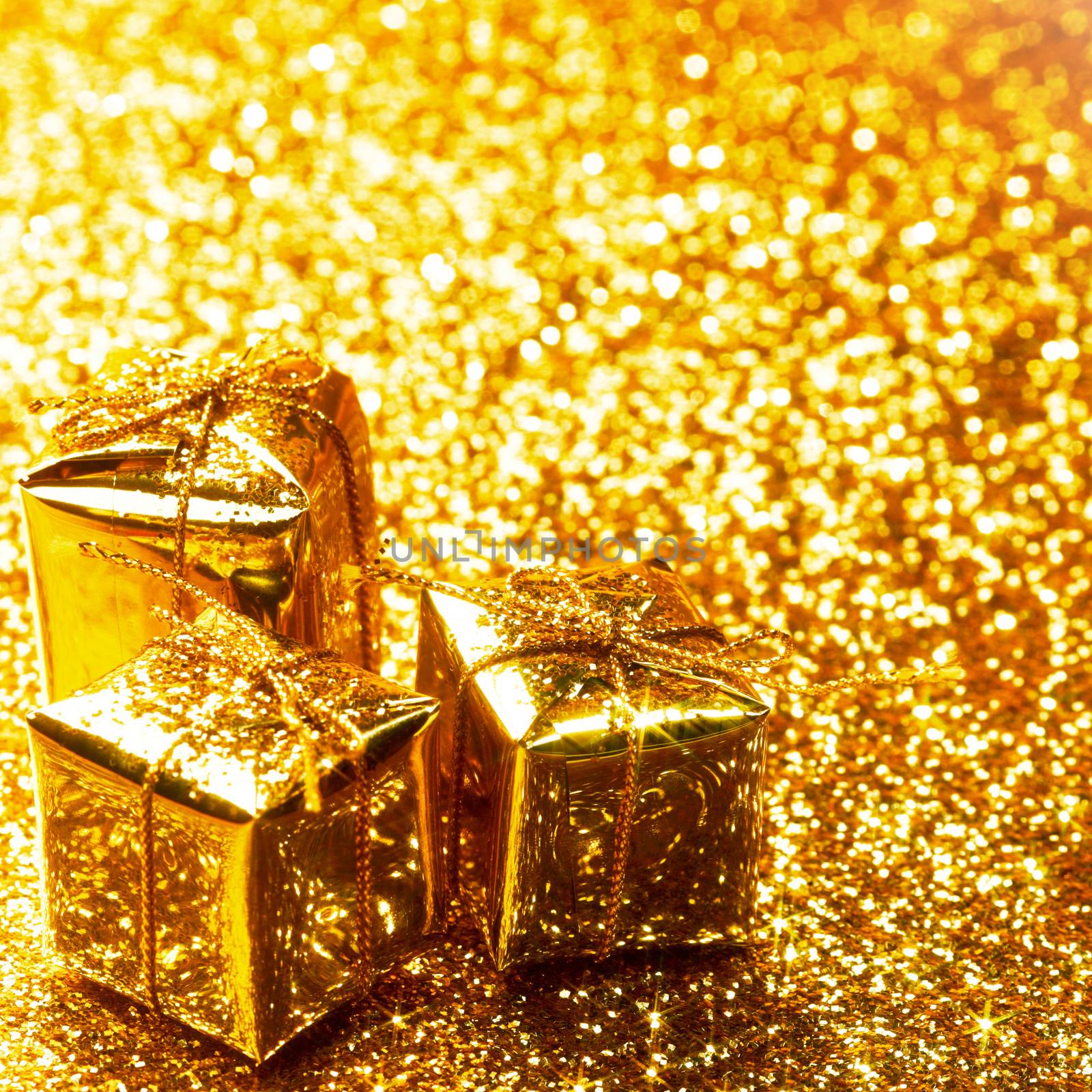 Decorative golden boxes with holiday gifts on shiny glitter background