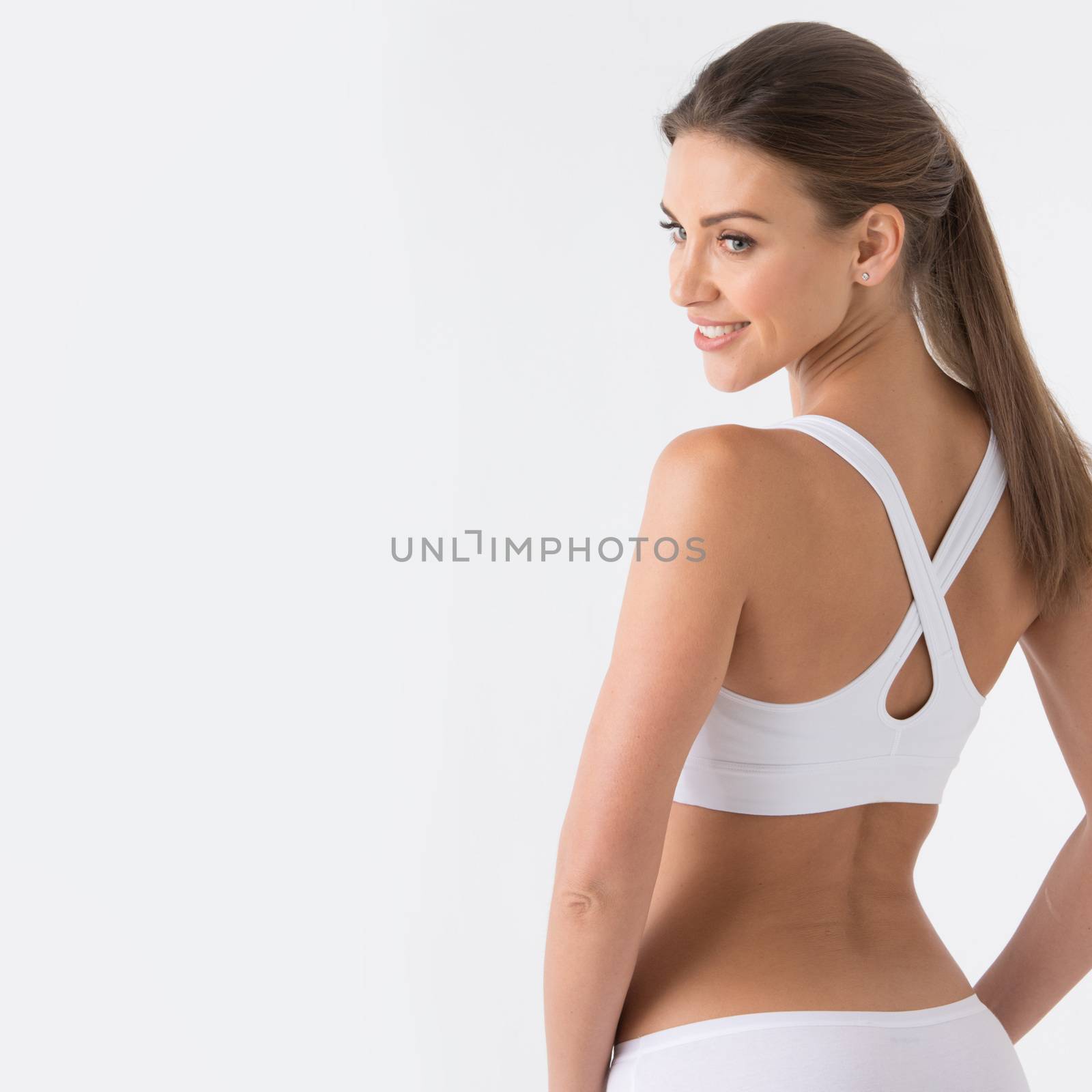 Young woman in white sport lingerie looking in profile . rear view , copy space for text