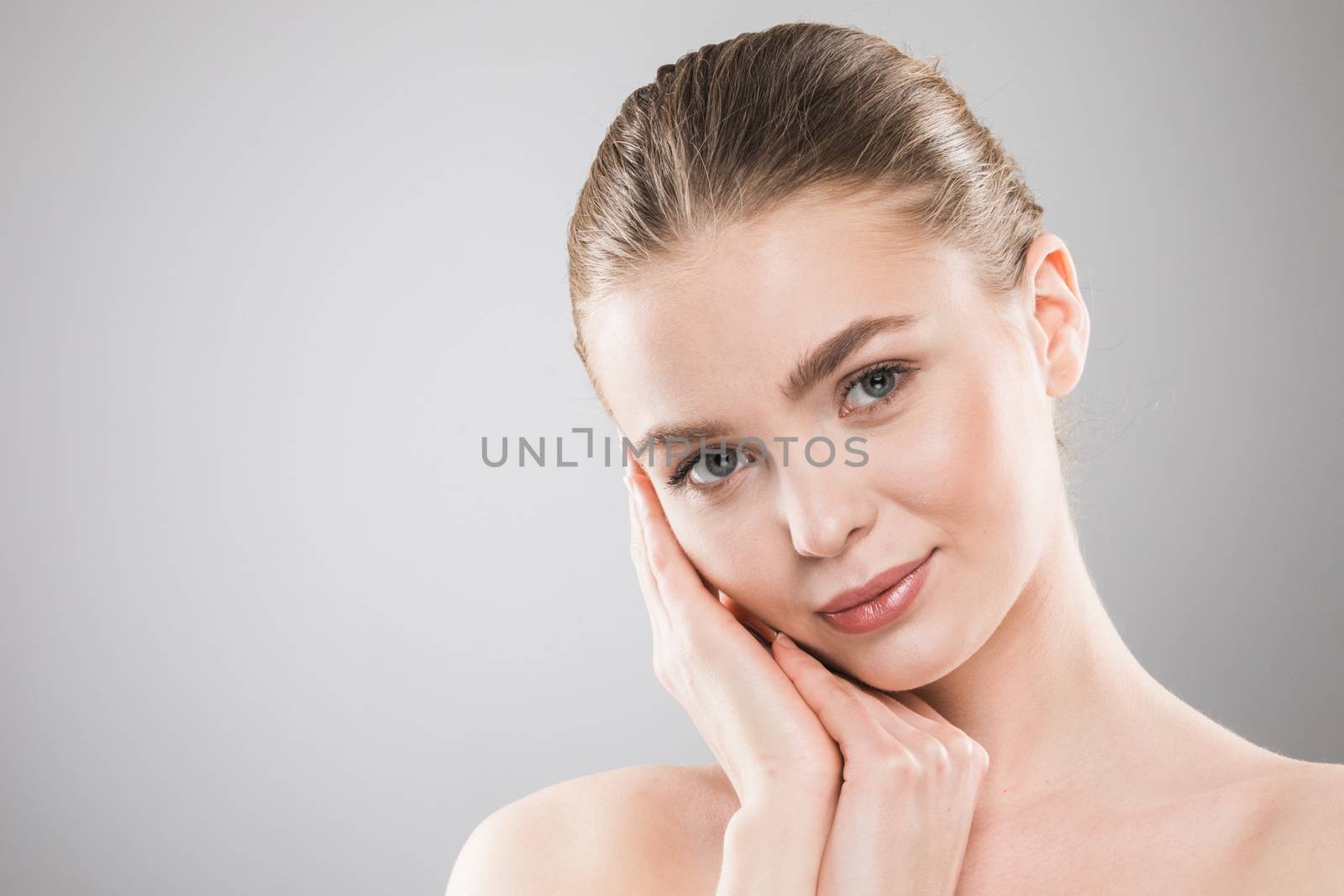 Beautiful young woman with clean fresh skin touch own face . Facial treatment , cosmetology , beauty and spa .