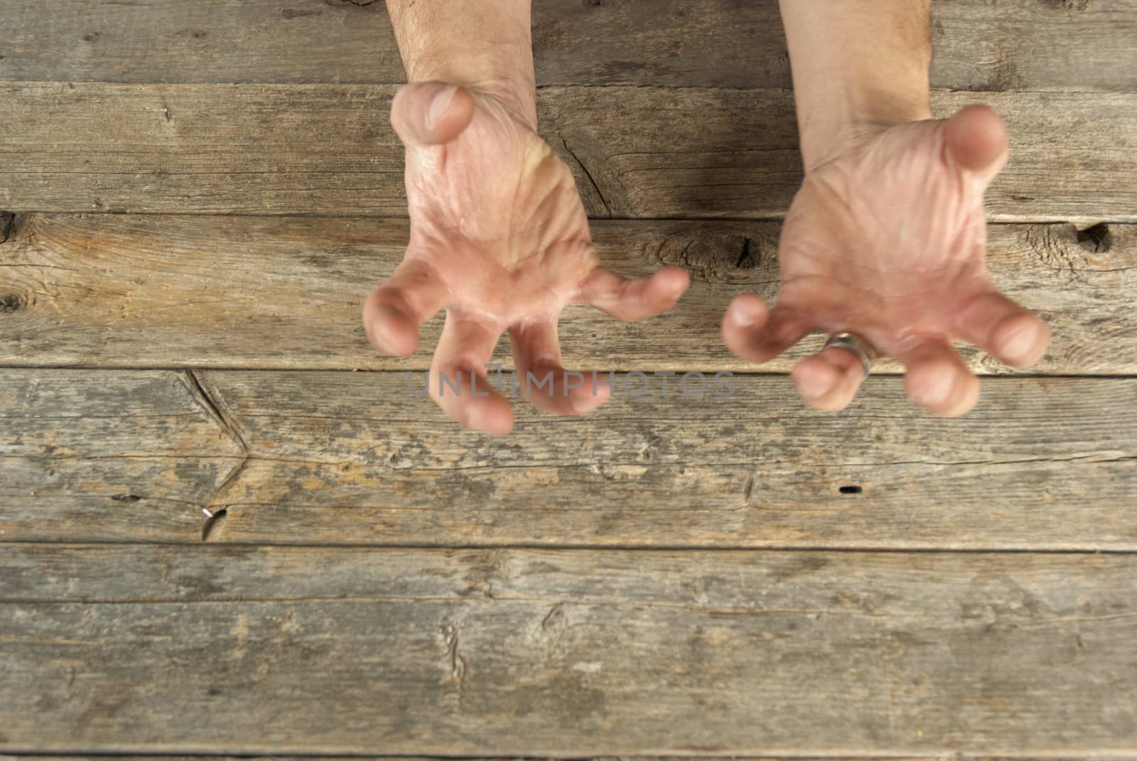 Man hand in claw gesture in a wood table/background