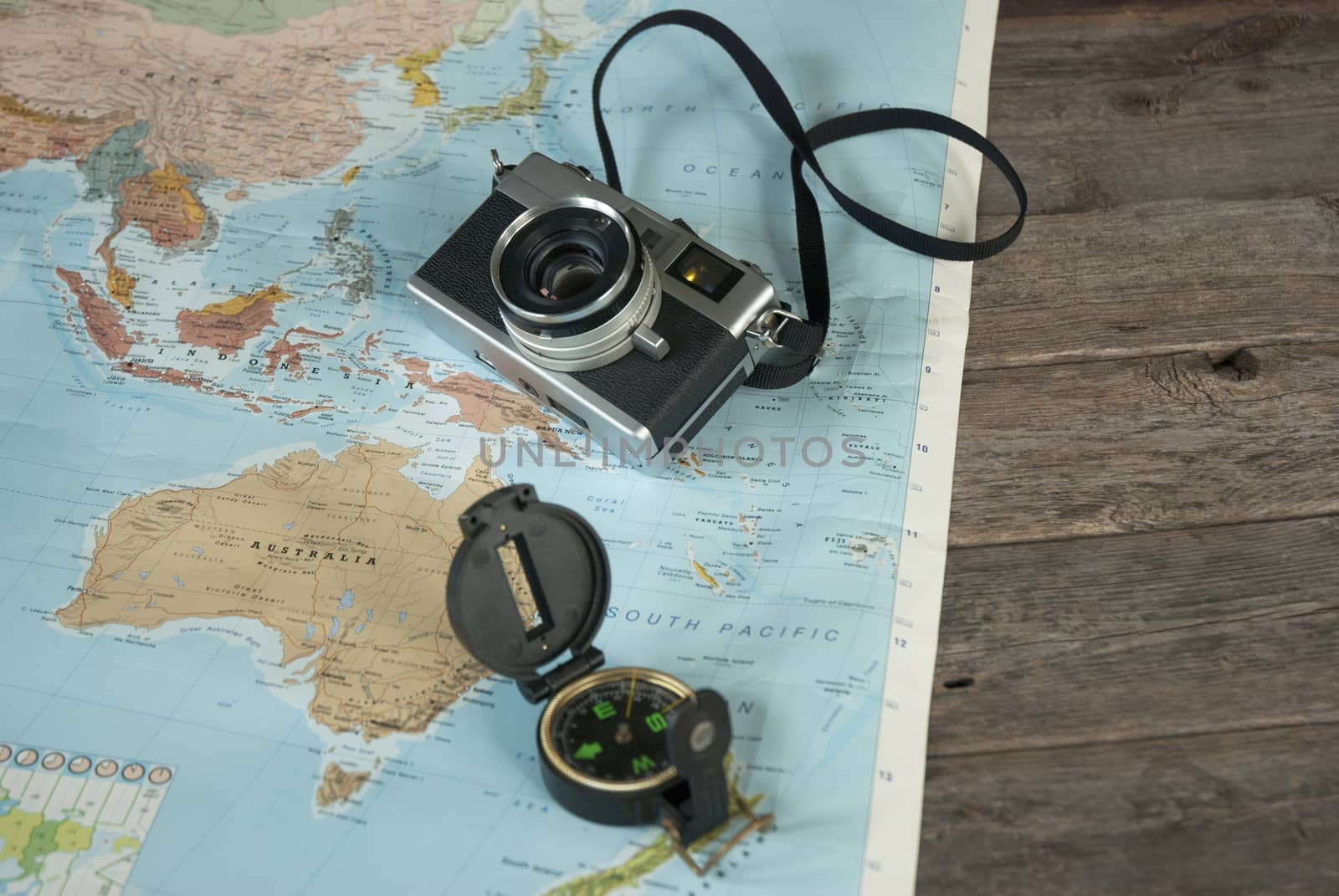 This image shows a world map, a compass and a camera for world travelers