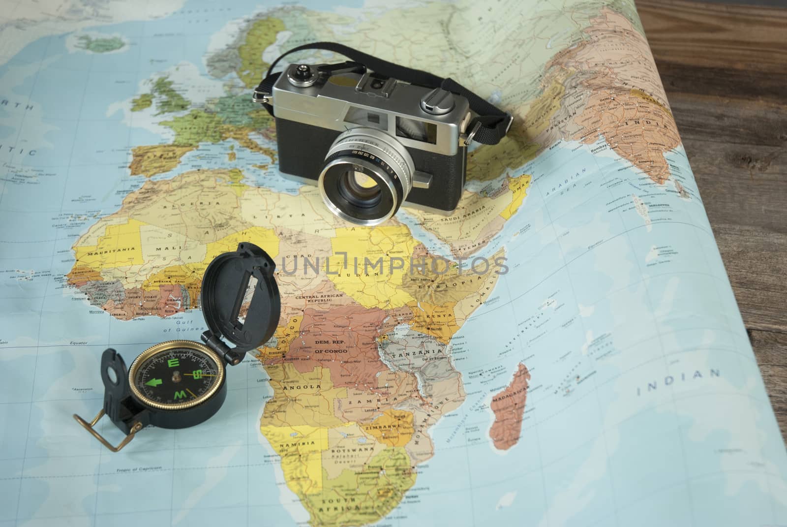 This image shows a world map, a compass and a camera for world travelers