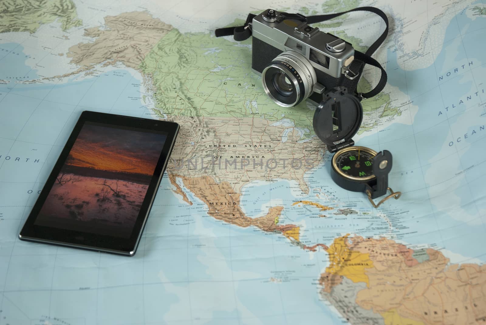 This image shows a world map, a compass and a camera for world travelers