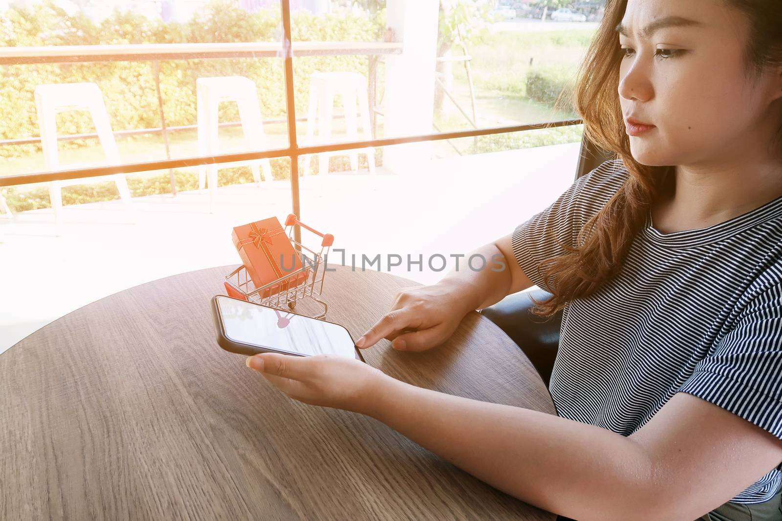 Woman and Small shopping cart with smartphone for Internet online shopping concept 