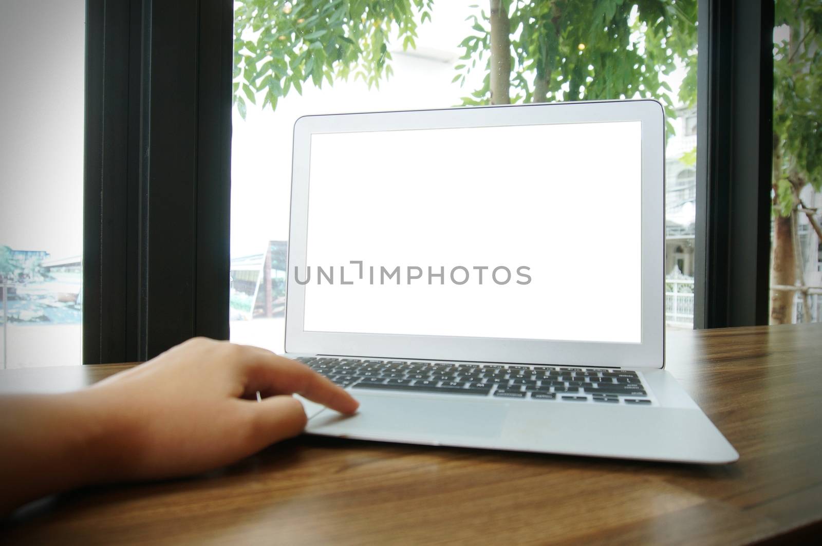 Laptop with blank screen on wooden table in front of coffeeshop  by peandben