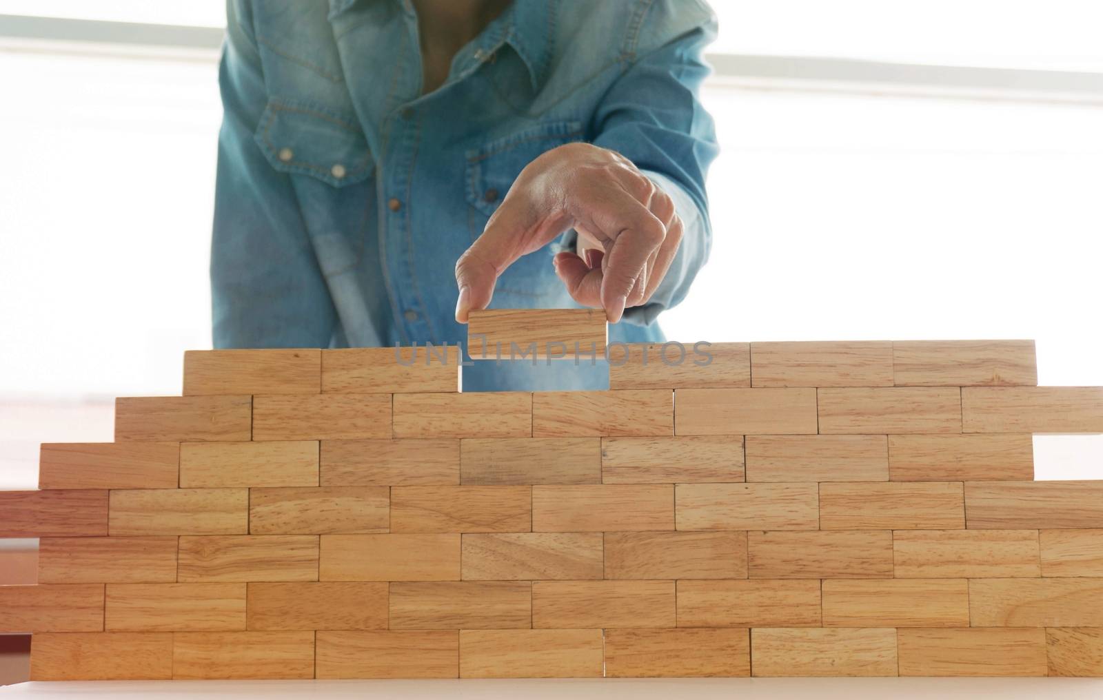 Woman in jeans shirt holding blocks wood game  Building a small  by peandben