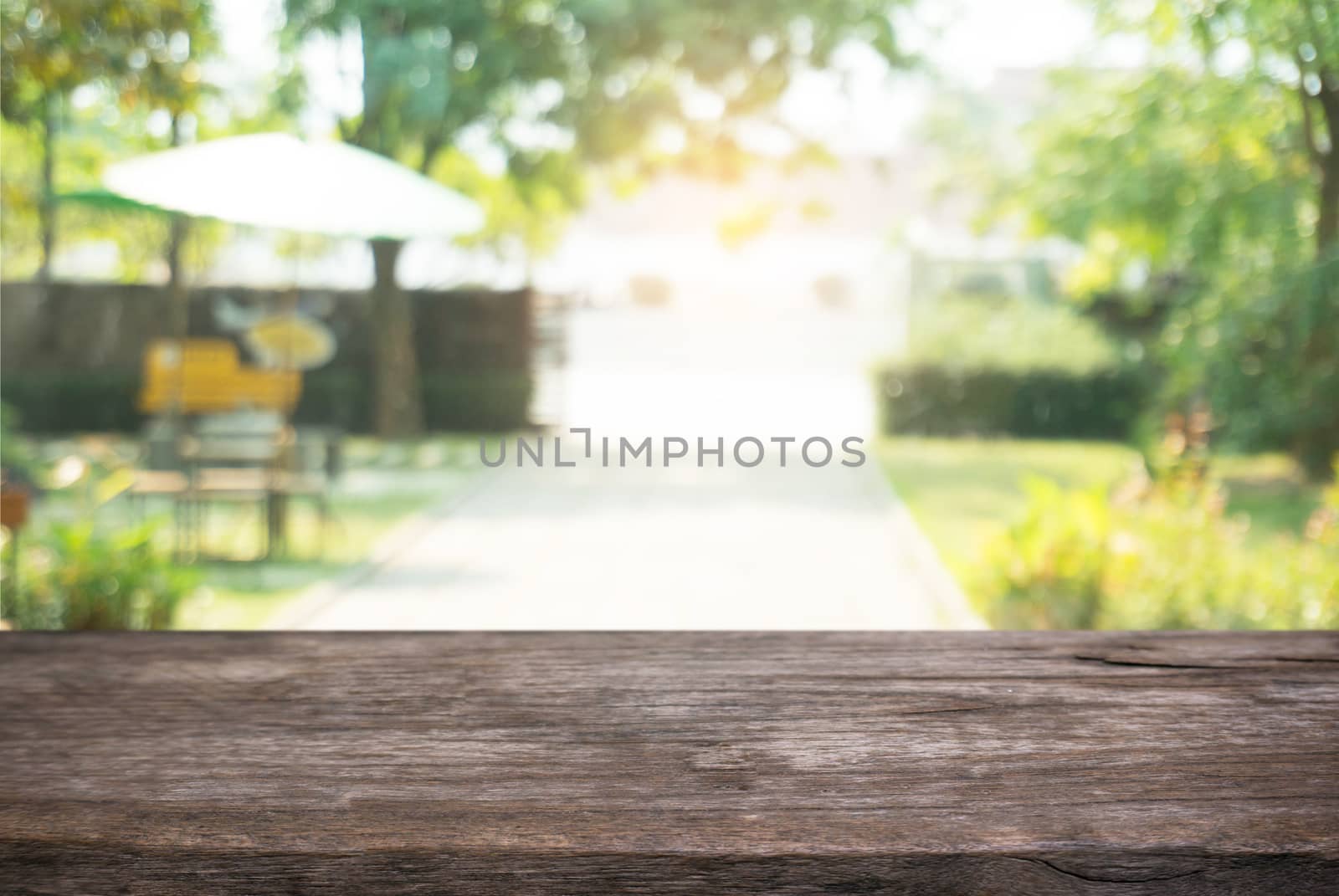 Image of wooden table in front of abstract blurred background of outdoor garden lights. can be used for display or montage your products.Mock up for display of product.