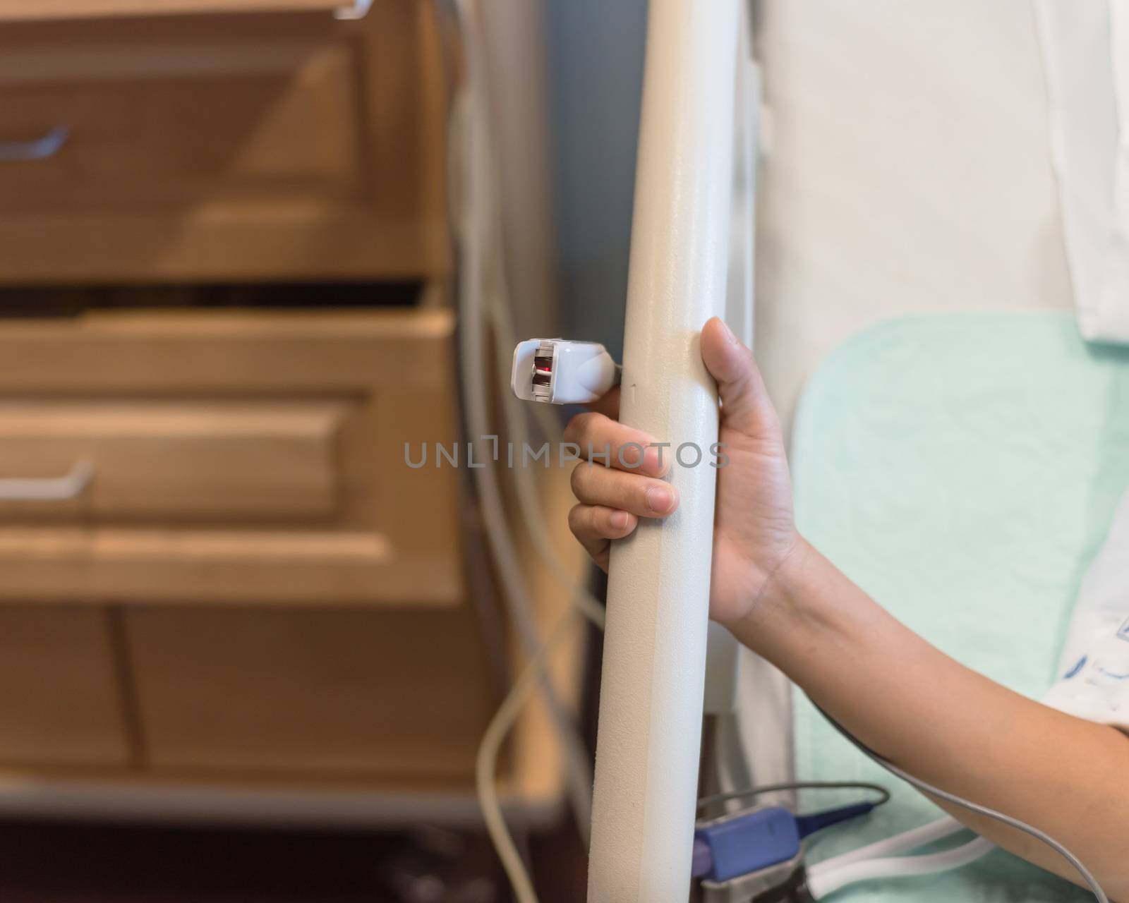 Asian woman patient wear fingertip pulse oximeter holding birthing bed bar at labor and delivery room in American hospital
