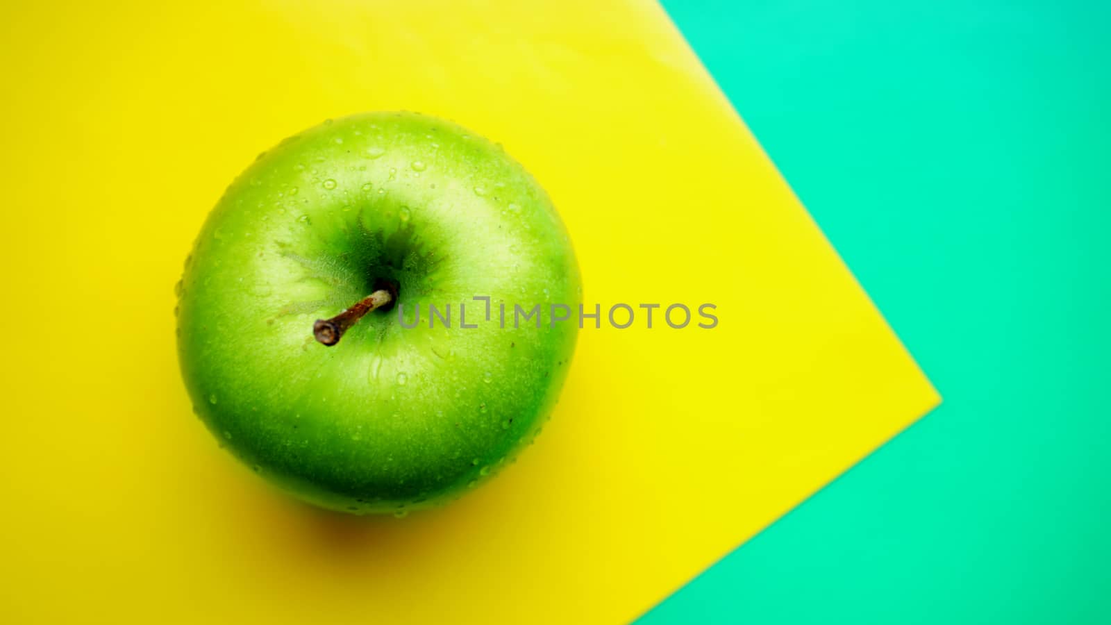 Green apple in water drops on yellow background isolated close up macro top view by natali_brill