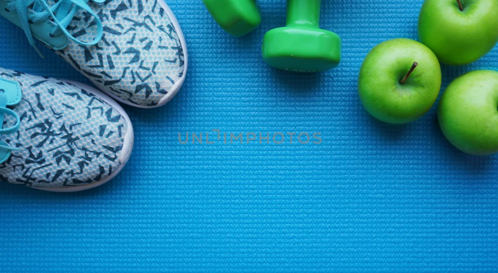 Sneakers, apples and dumbbells fitness on a blue background. by natali_brill