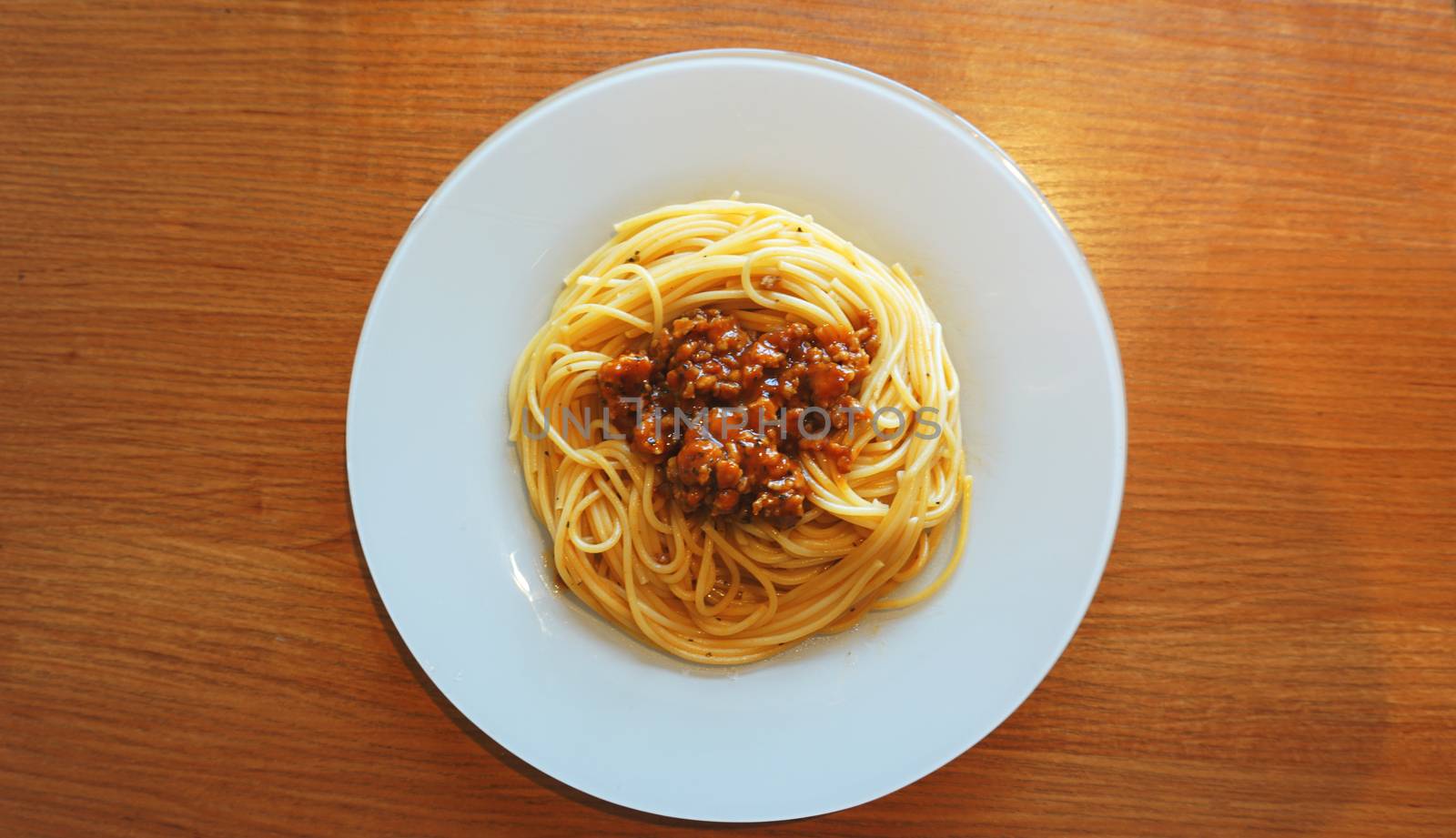 Plate of delicious spaghetti Bolognaise or Bolognese with savory minced beef and tomato sauce garnished, overhead view