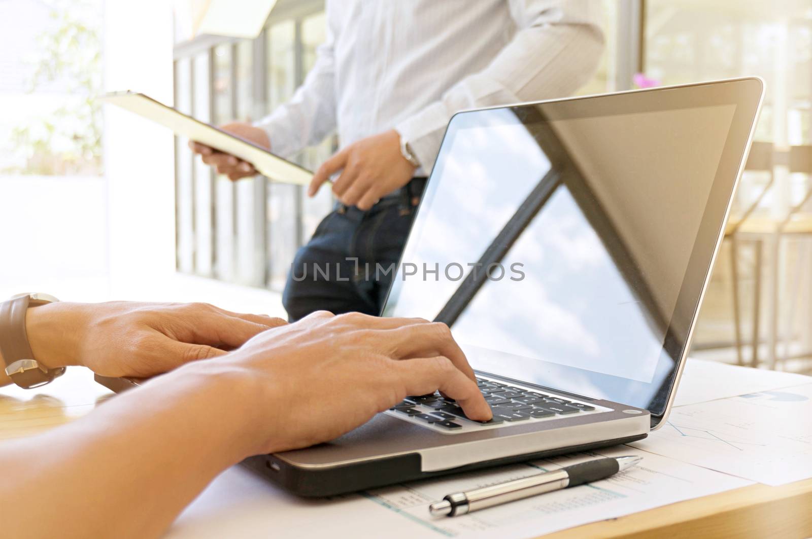 image of a young man working on his laptop in library, rear view of business man hands busy using laptop at office desk, young male student typing on computer sitting at wooden table.