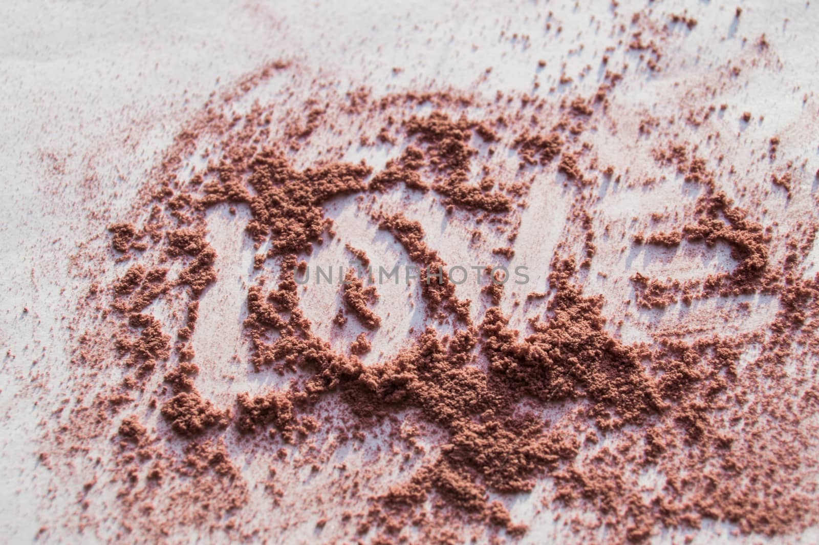 The word love is written on a loose powder makeup, white background.