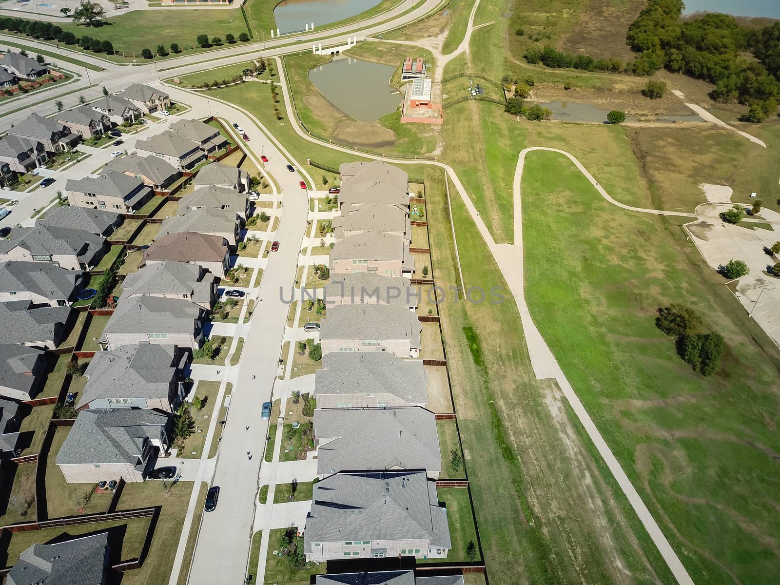 Top view new established neighborhood with brand new houses near park and pathway trail. Flyover residential area in suburban Dallas, Texas, USA
