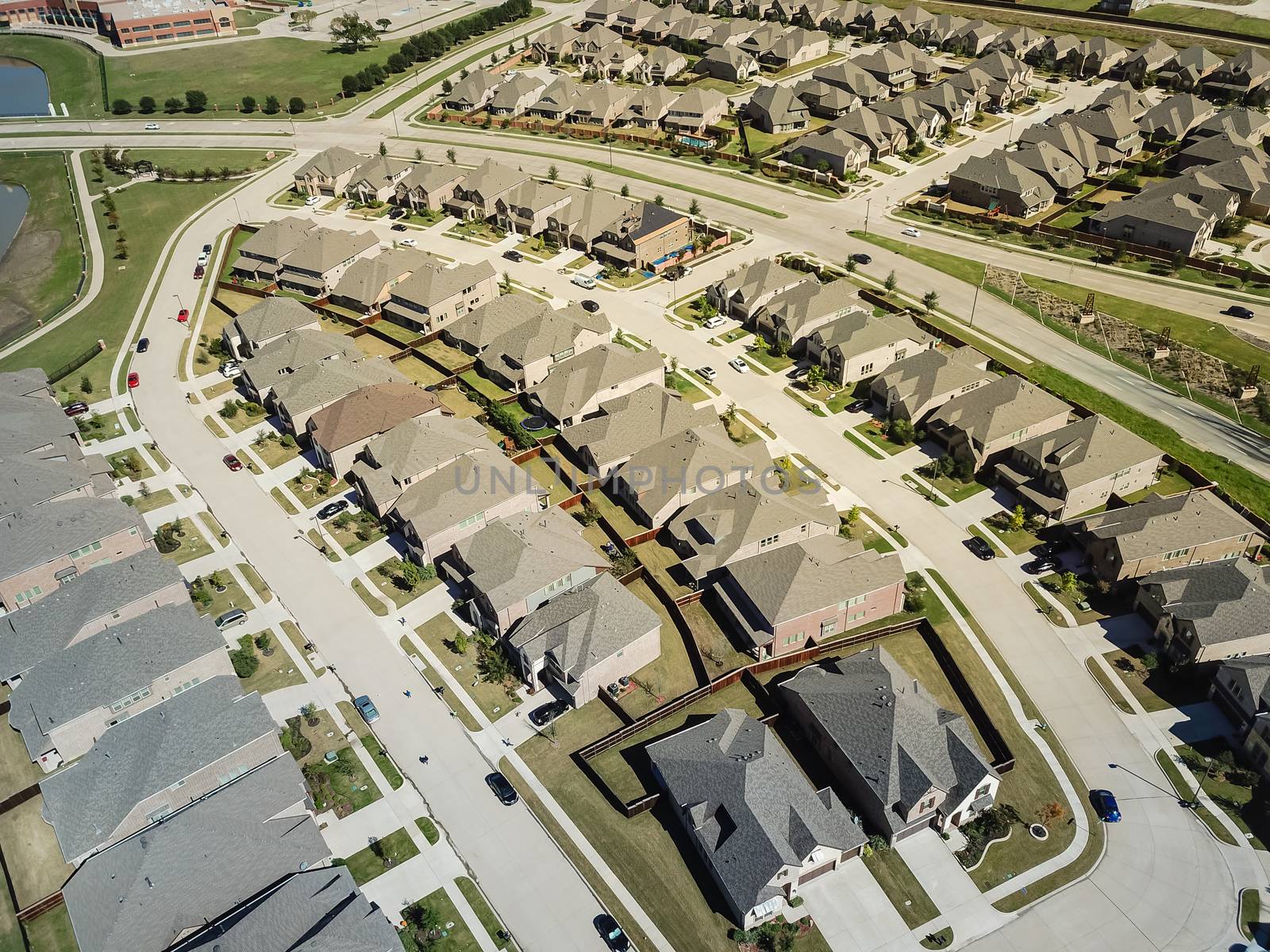 Aerial view new residential area near school district in North Dallas, Texas, USA. Flyover row of brand new single-family houses with gardens