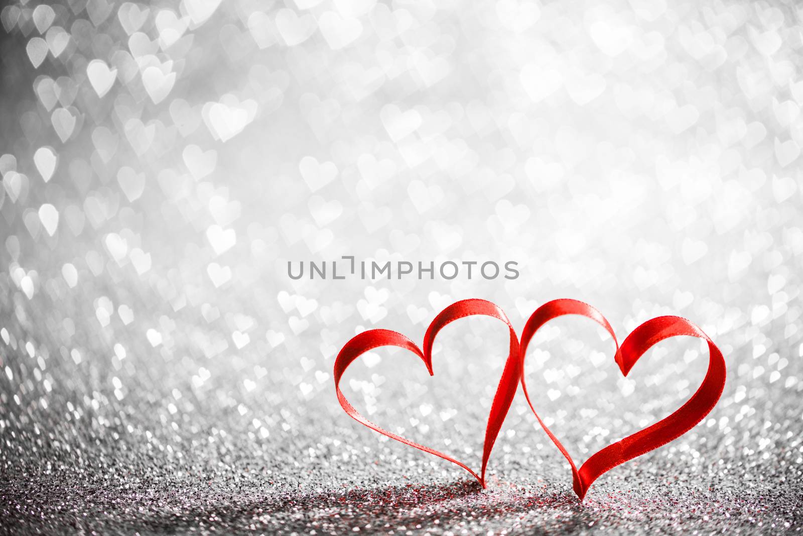 Two red ribbon hearts on glowing bokeh lights background
