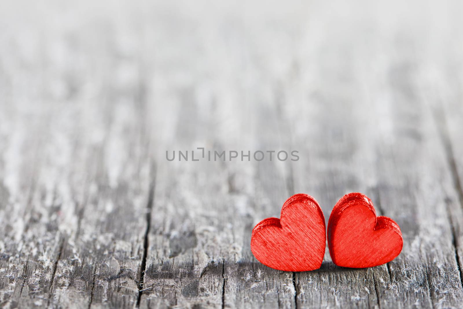 Two red painted handmade hearts on old cracked wooden background with copy space for text