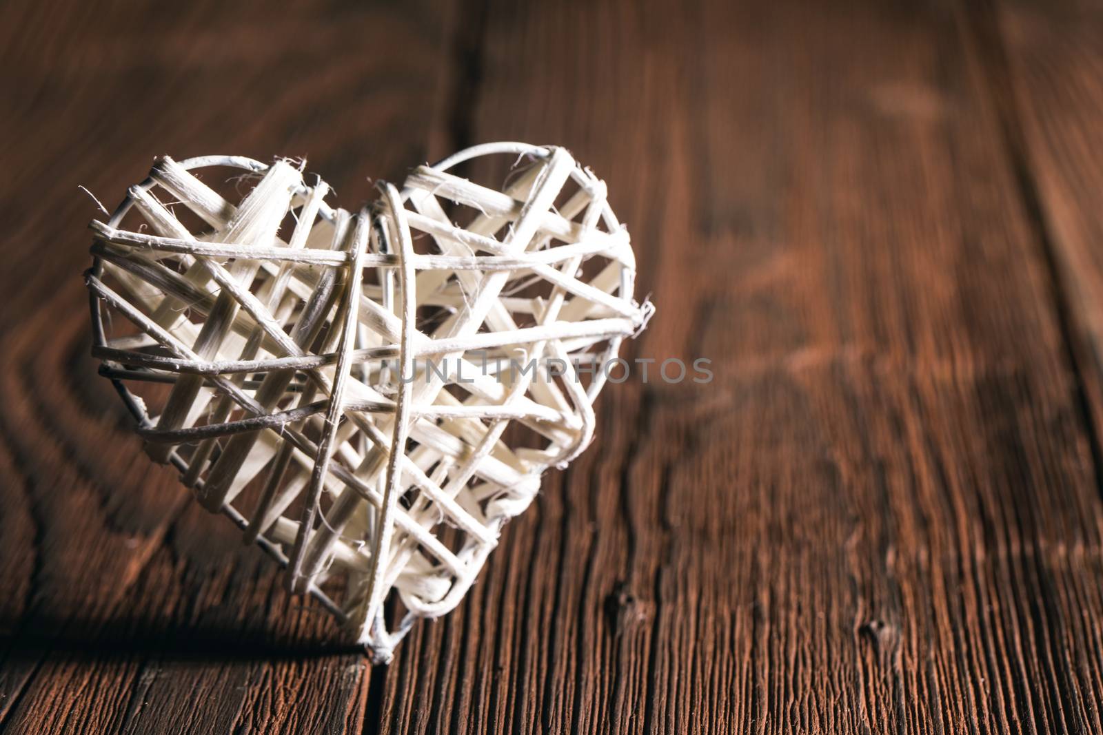 White wicker heart on old wooden background Valentine day
