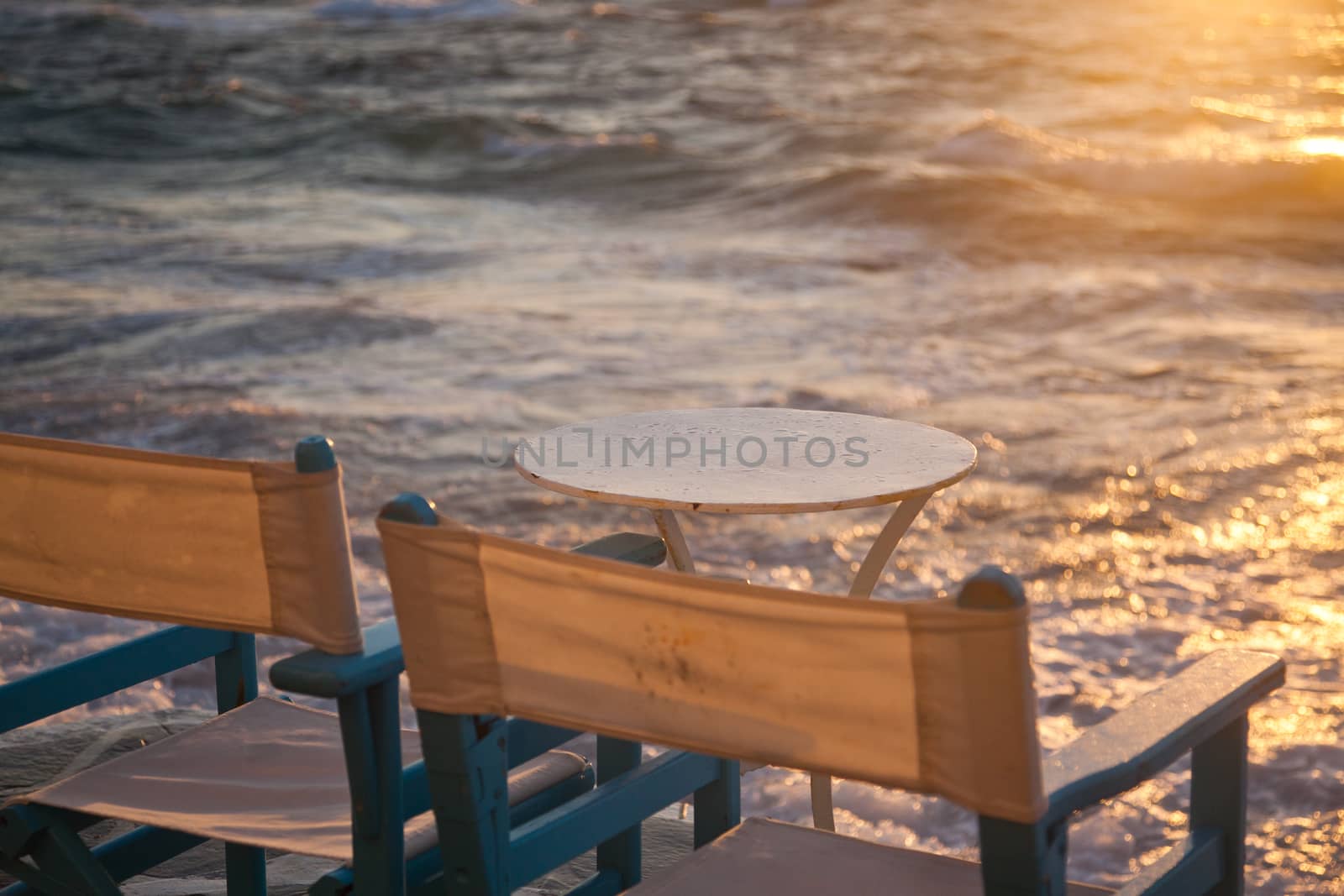 table and chairs near the waves at sunset - beach holiday by melis