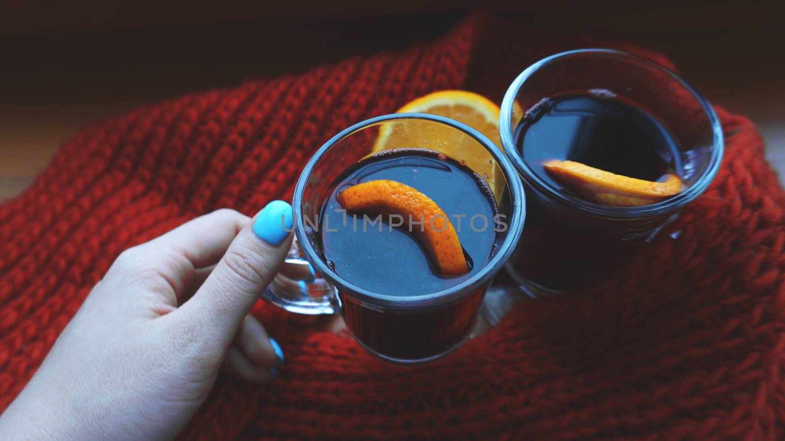 Woman holding mulled wine with spices and citrus fruit in her hand, close up by natali_brill