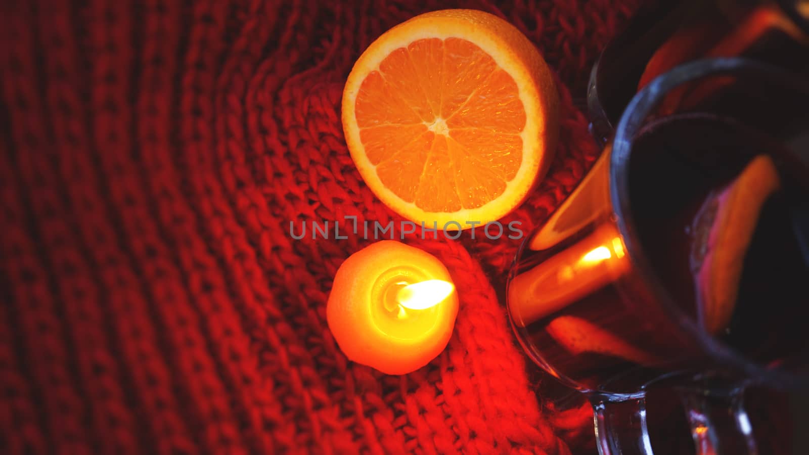 Mulled wine in glass mugs, burning candle on a dark red background. Red Hot wine by natali_brill