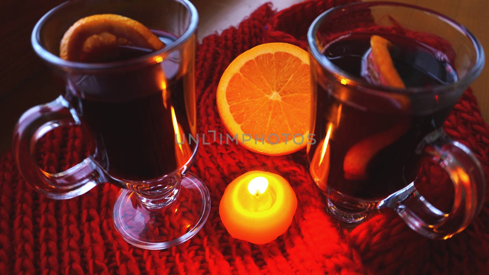 Mulled wine in glass mugs, burning candle on a dark red background. Red Hot wine by natali_brill