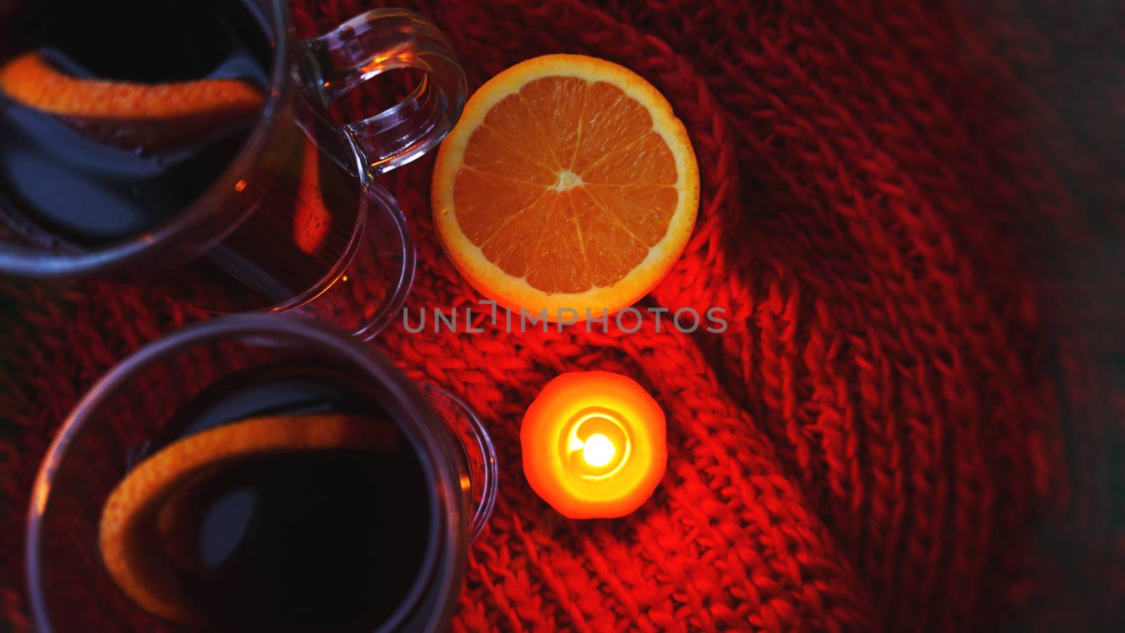 Mulled wine in glass mugs, burning candle on a dark red background. Red Hot wine by natali_brill