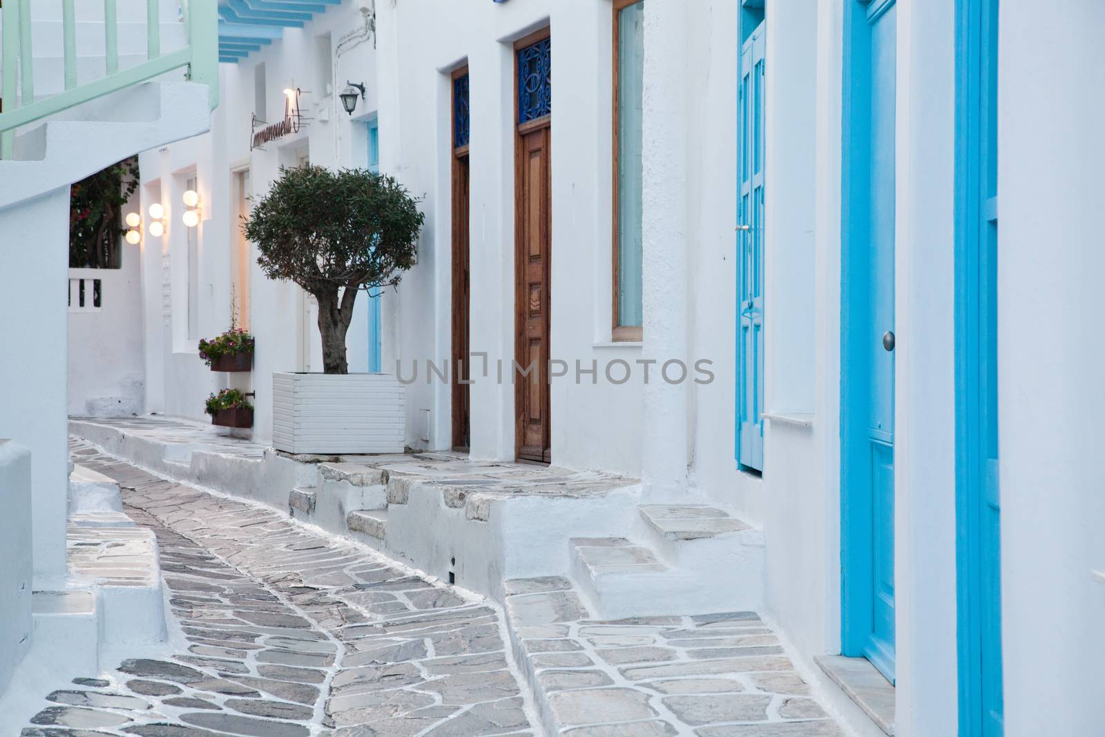 traditional narrow street in Mykonos with blue doors and white walls