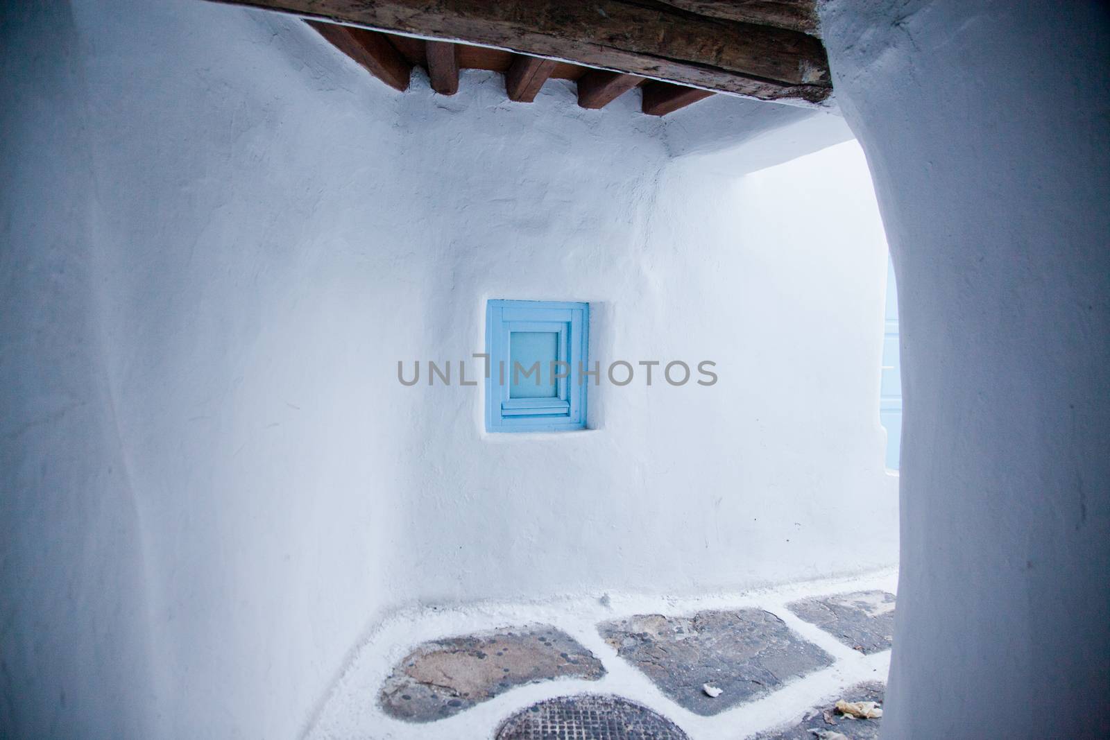 traditional narrow street in Mykonos with blue doors and white walls