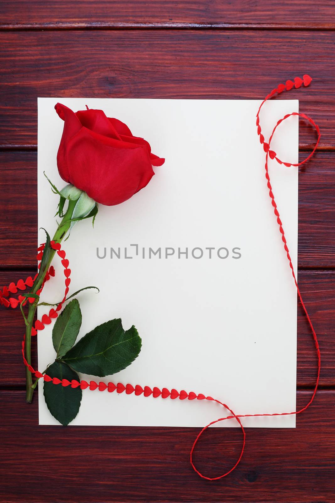 Red rose, paper and hearts ribbon on dark wooden background, Valentines day concept