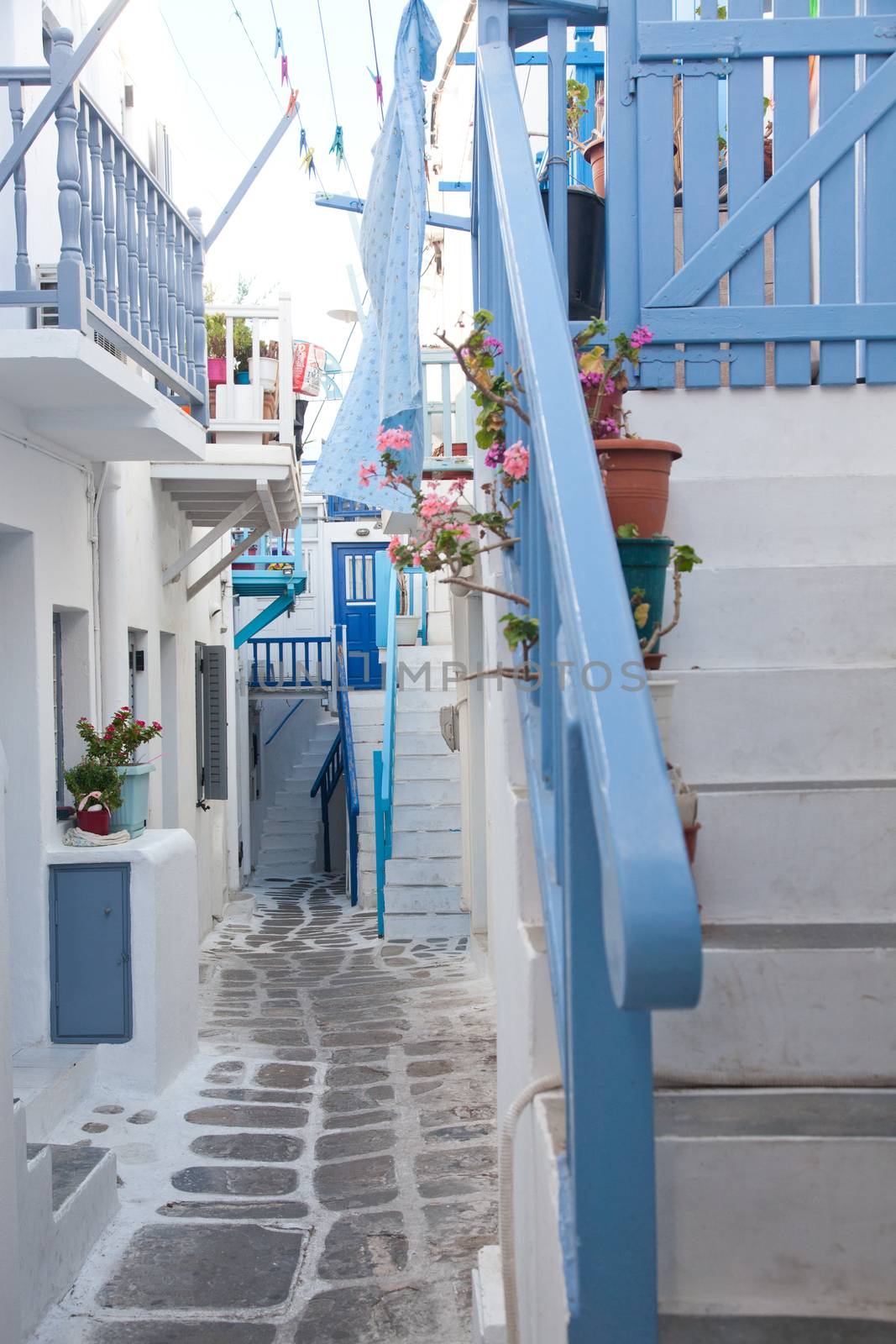 traditional narrow street in Mykonos with blue doors and white walls