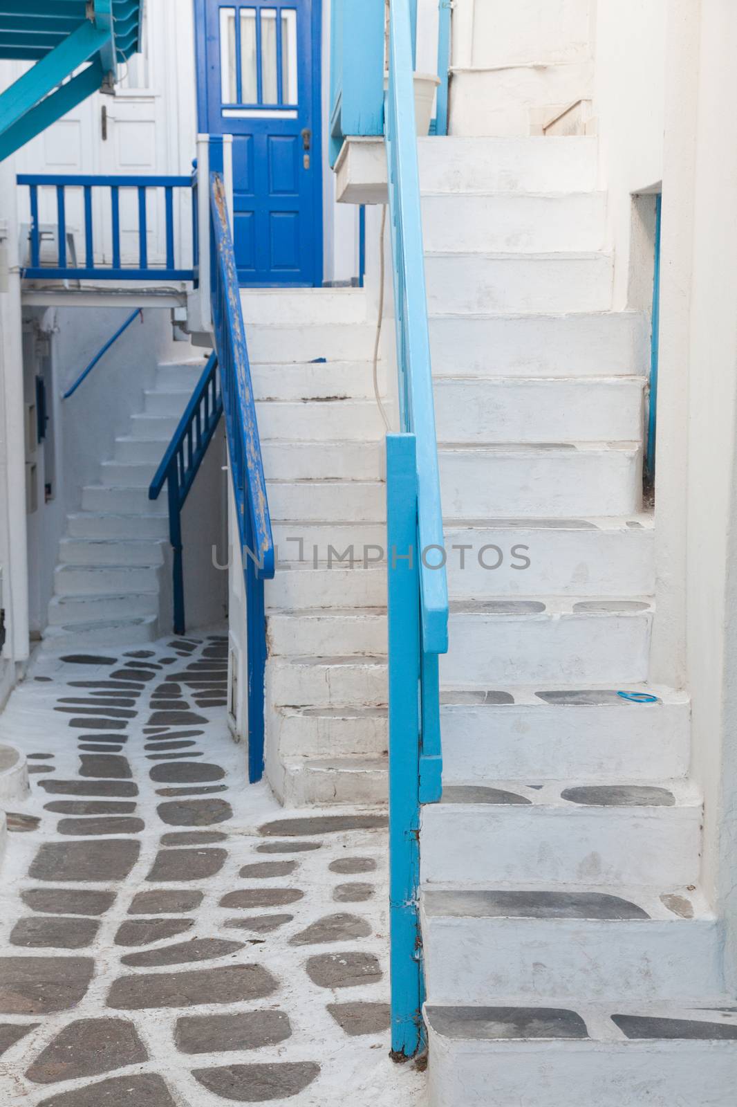 traditional narrow street in Mykonos with blue doors and white walls