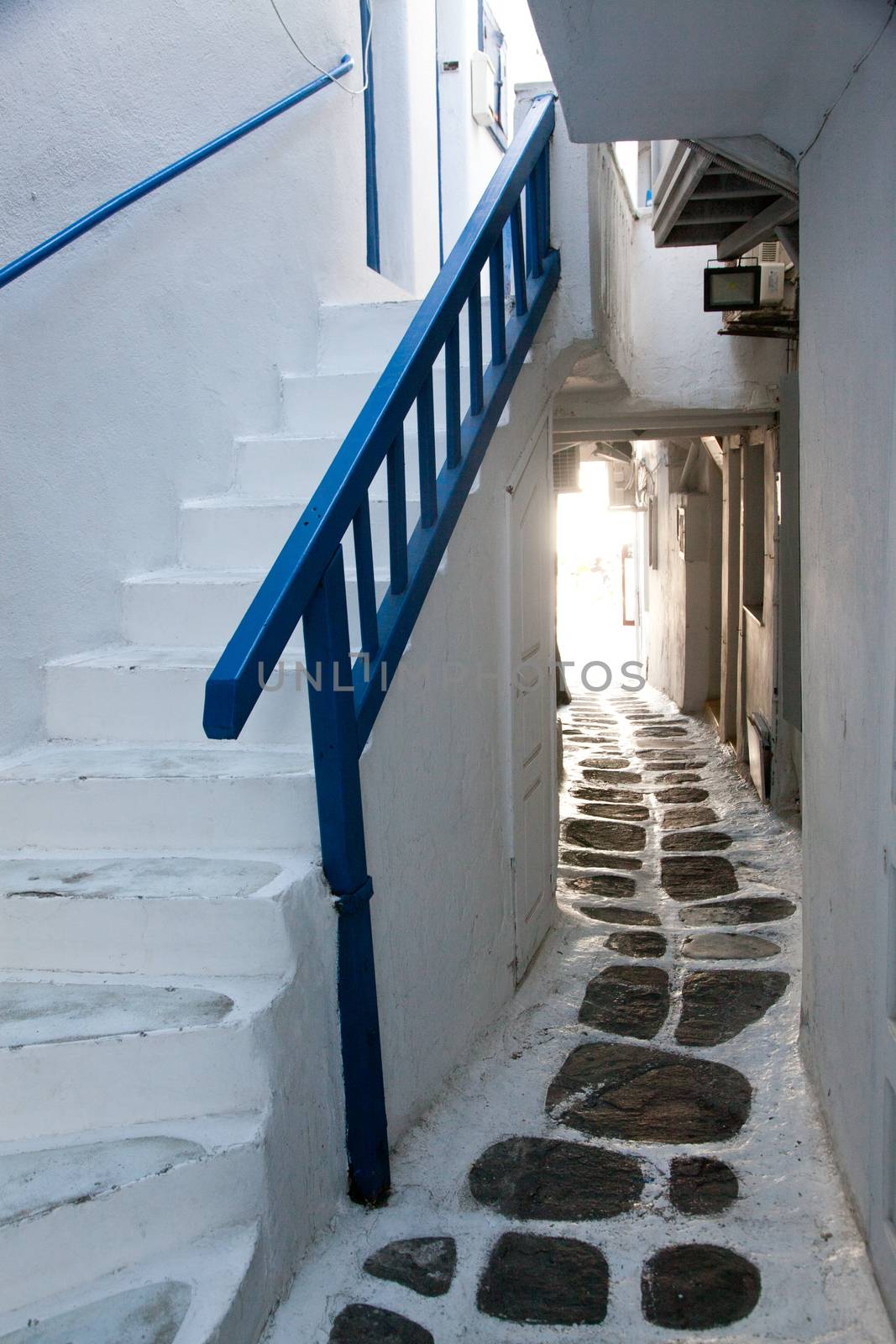 traditional narrow street in Mykonos with blue doors and white walls