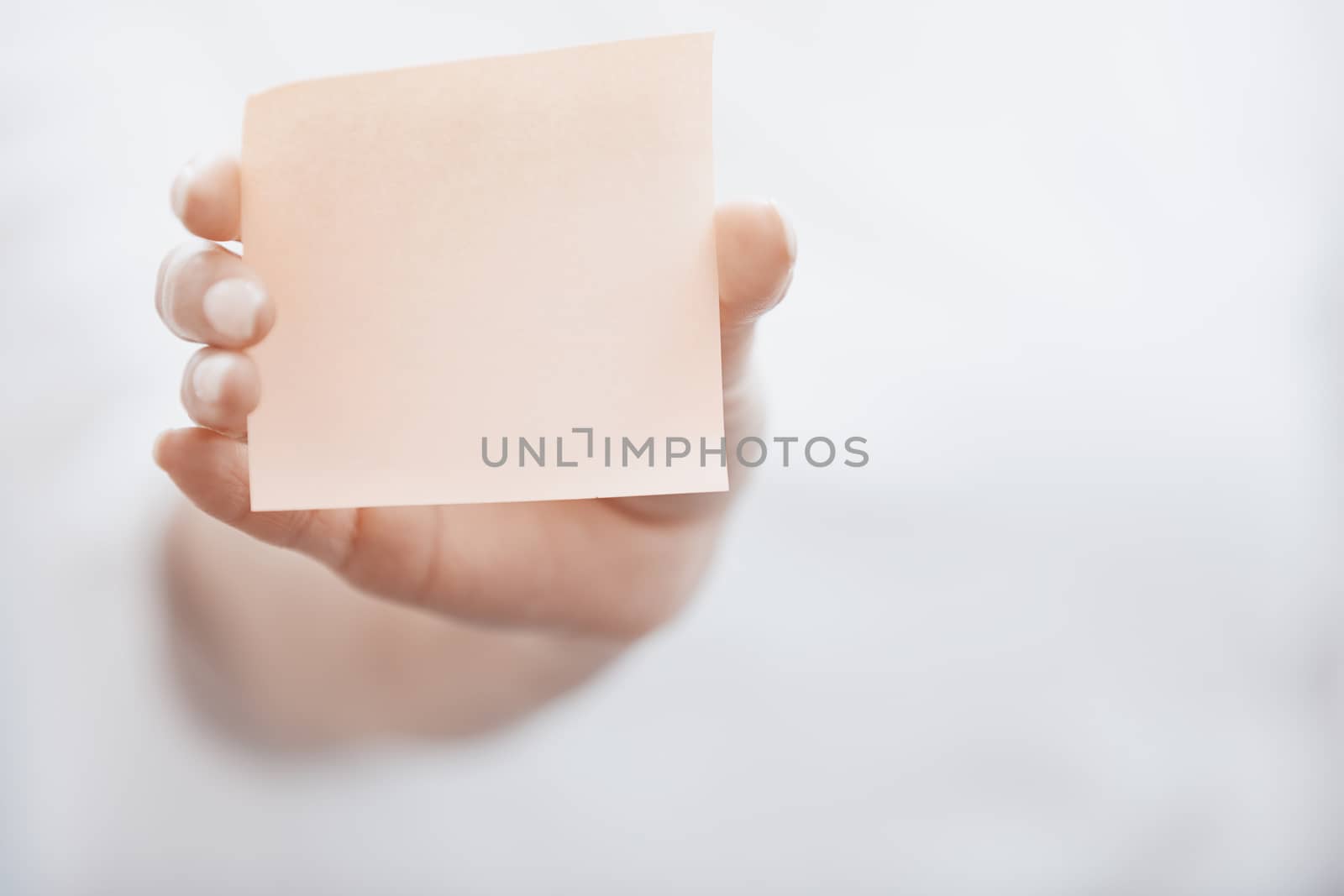 Human hand holding adhesive note by Novic