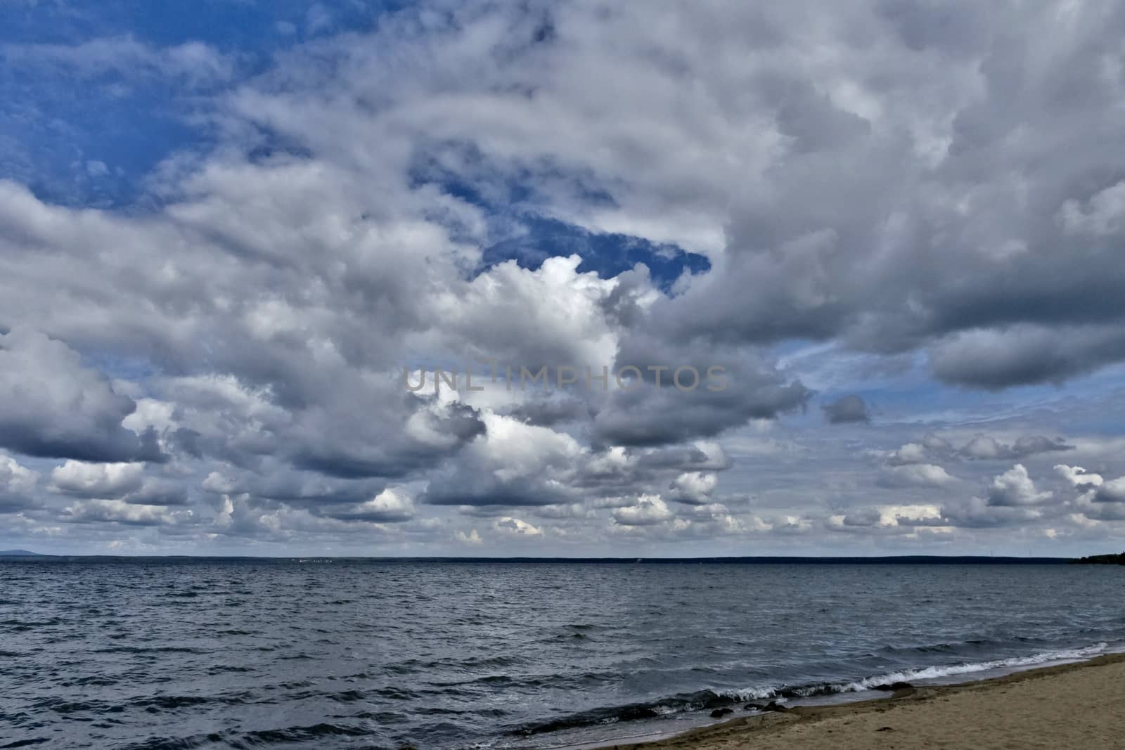 day lake in gray-white cloudy weather, South Ural, Uvildy, in the distance are seen the Ural mountains