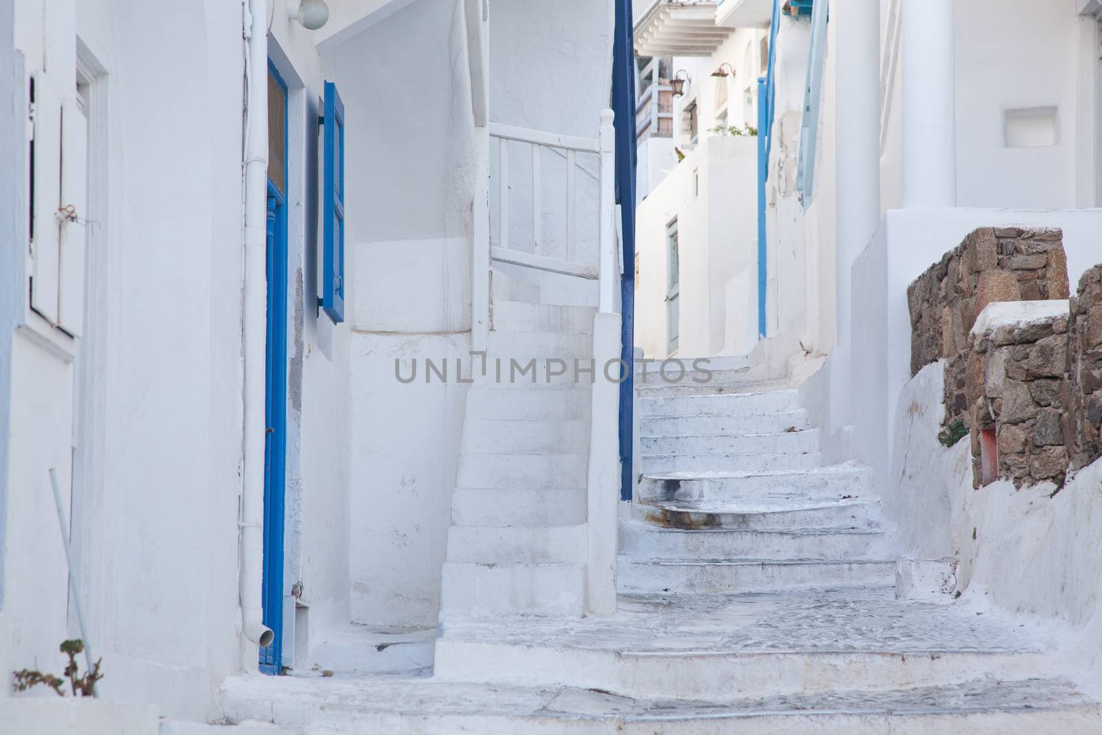 traditional narrow street in Mykonos with blue doors and white walls