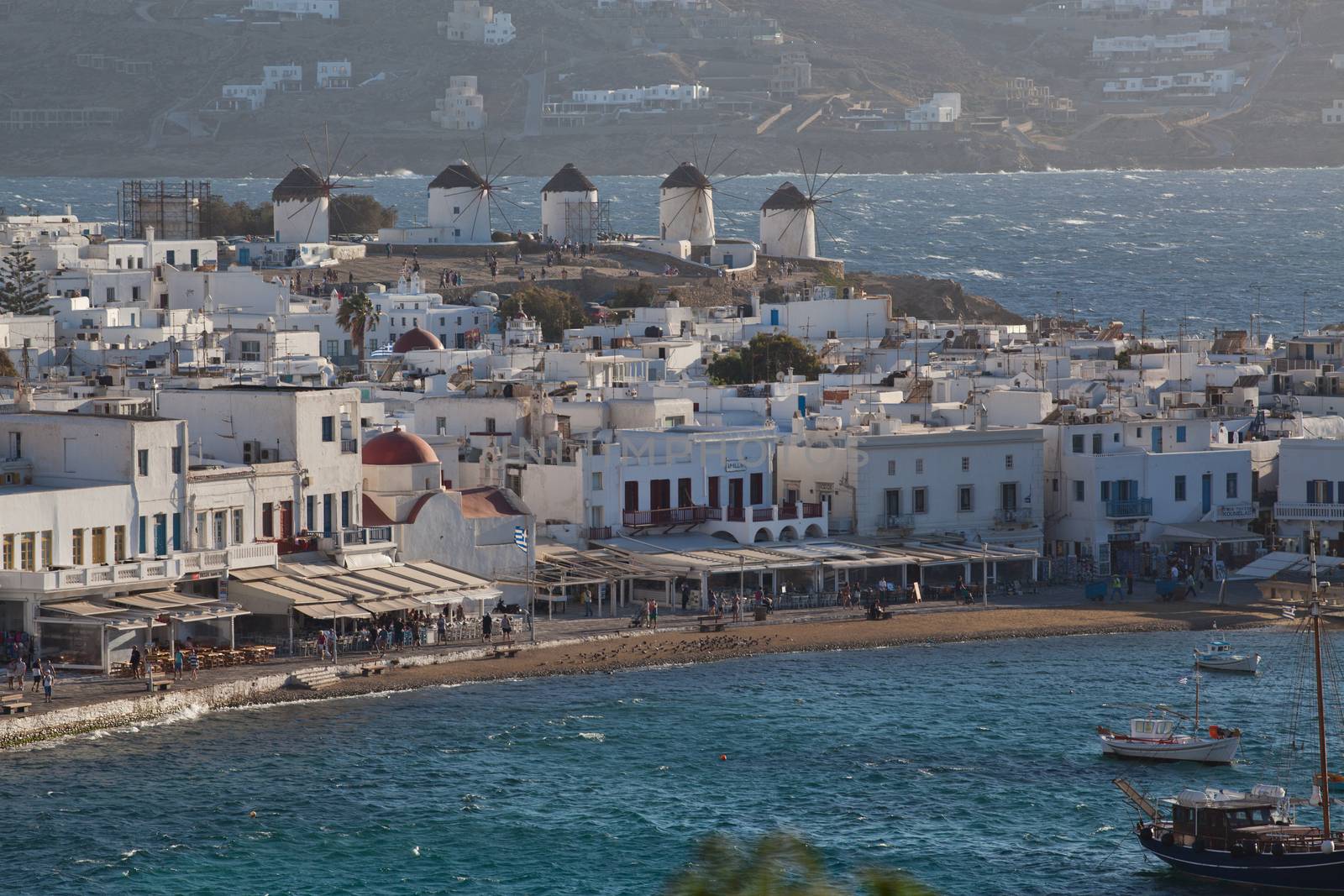 panoramic view of the Mykonos town harbor with famous windmills from the above hills on a sunny summer day, Mykonos, Cyclades, Greece 