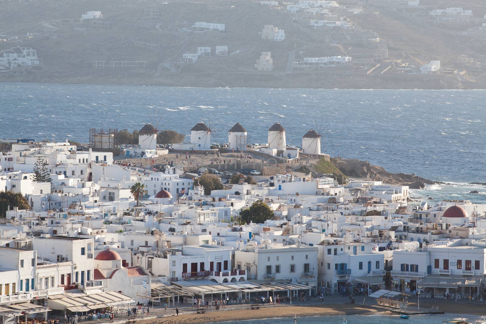 panoramic view of the Mykonos town harbor with famous windmills from the above hills on a sunny summer day, Mykonos, Cyclades, Greece 